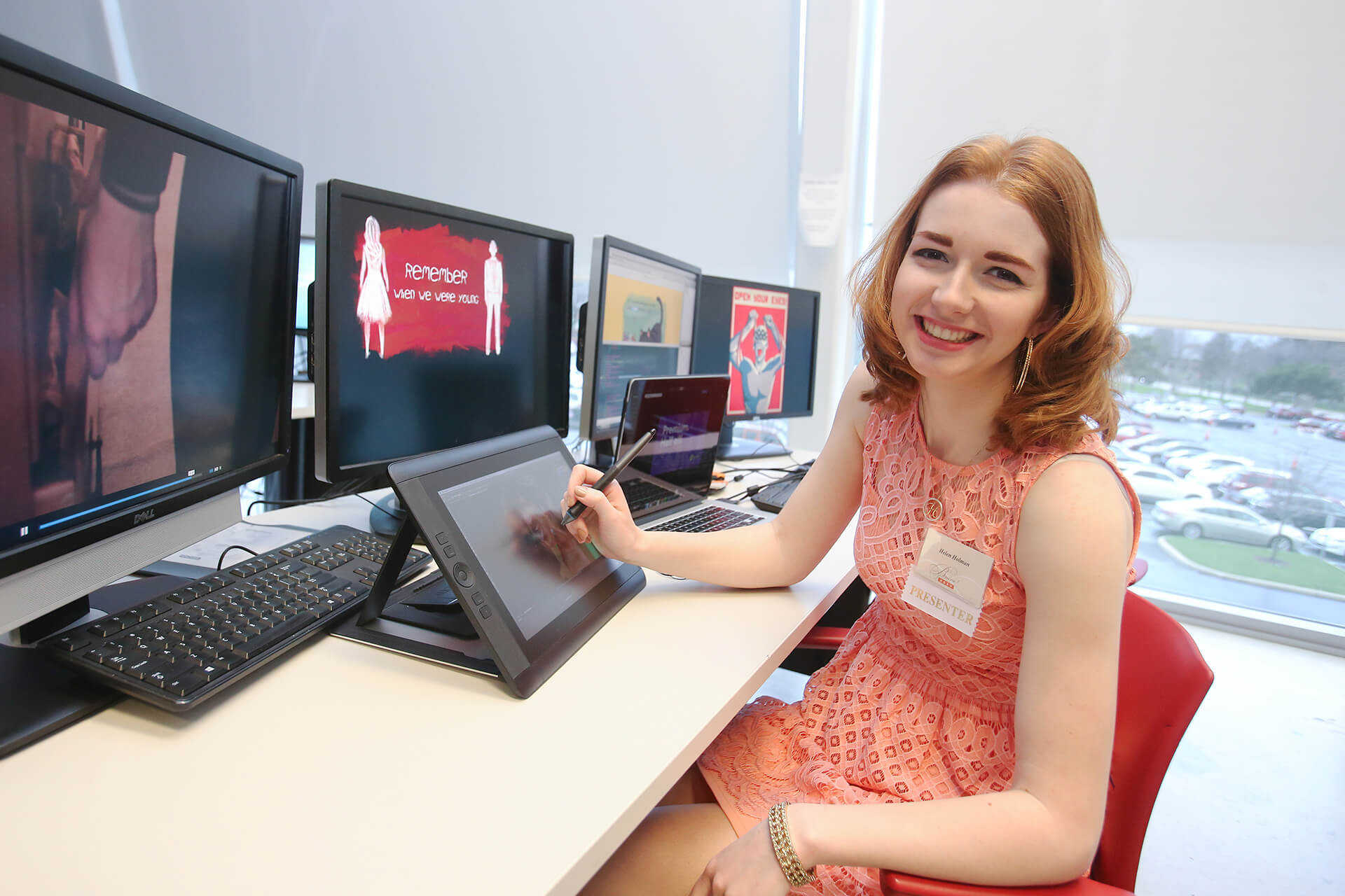 Student sitting at a compuster while drawing on a tablet.