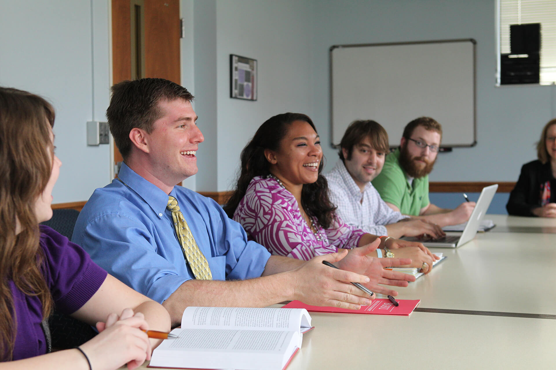 A row of students sitting at a table and talking.