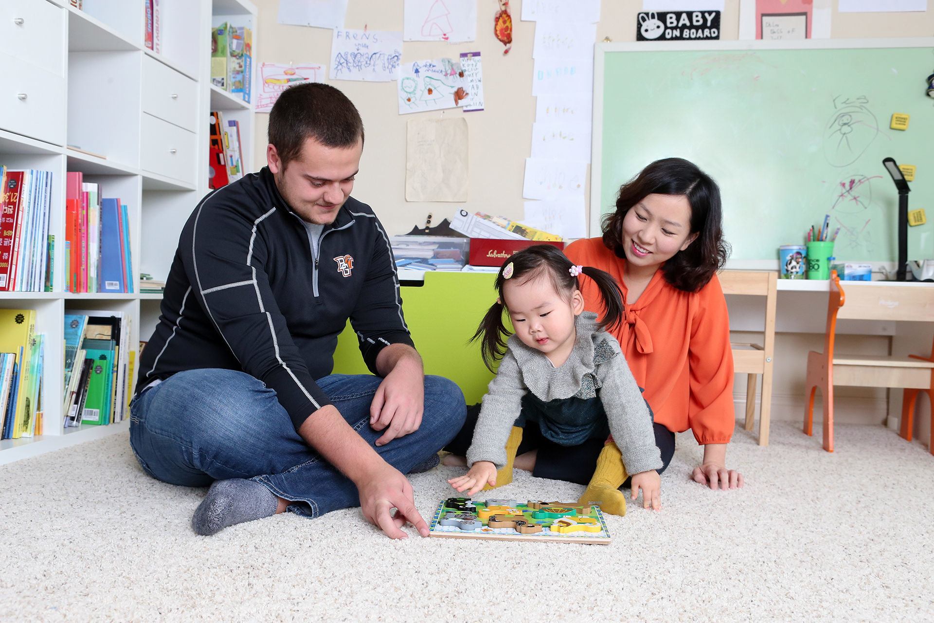 An teacher sits with a mother and little girl in a classroom