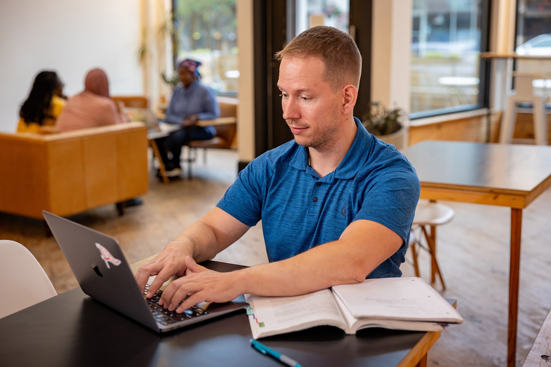 A man sits at a table and works on a laptop