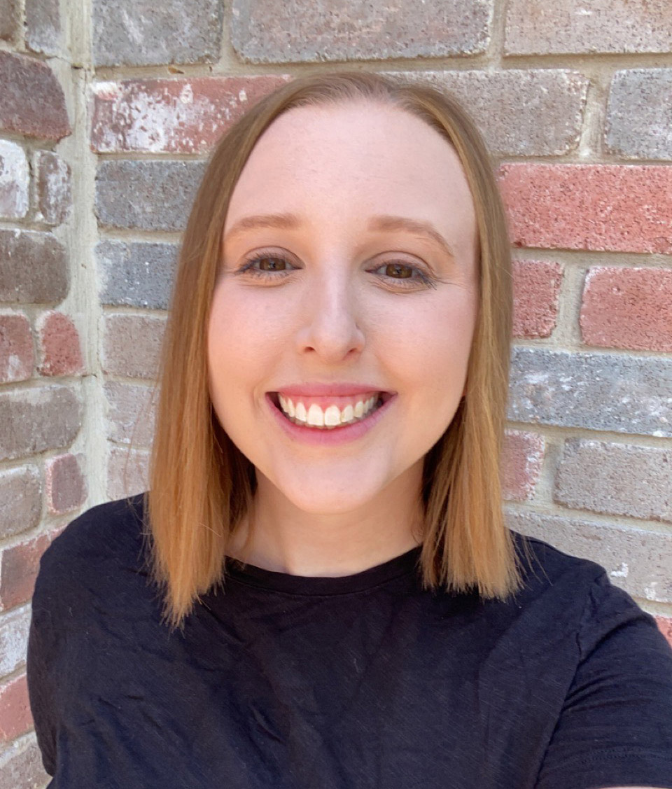 Jenna Lahood smiles in front of a brick wall