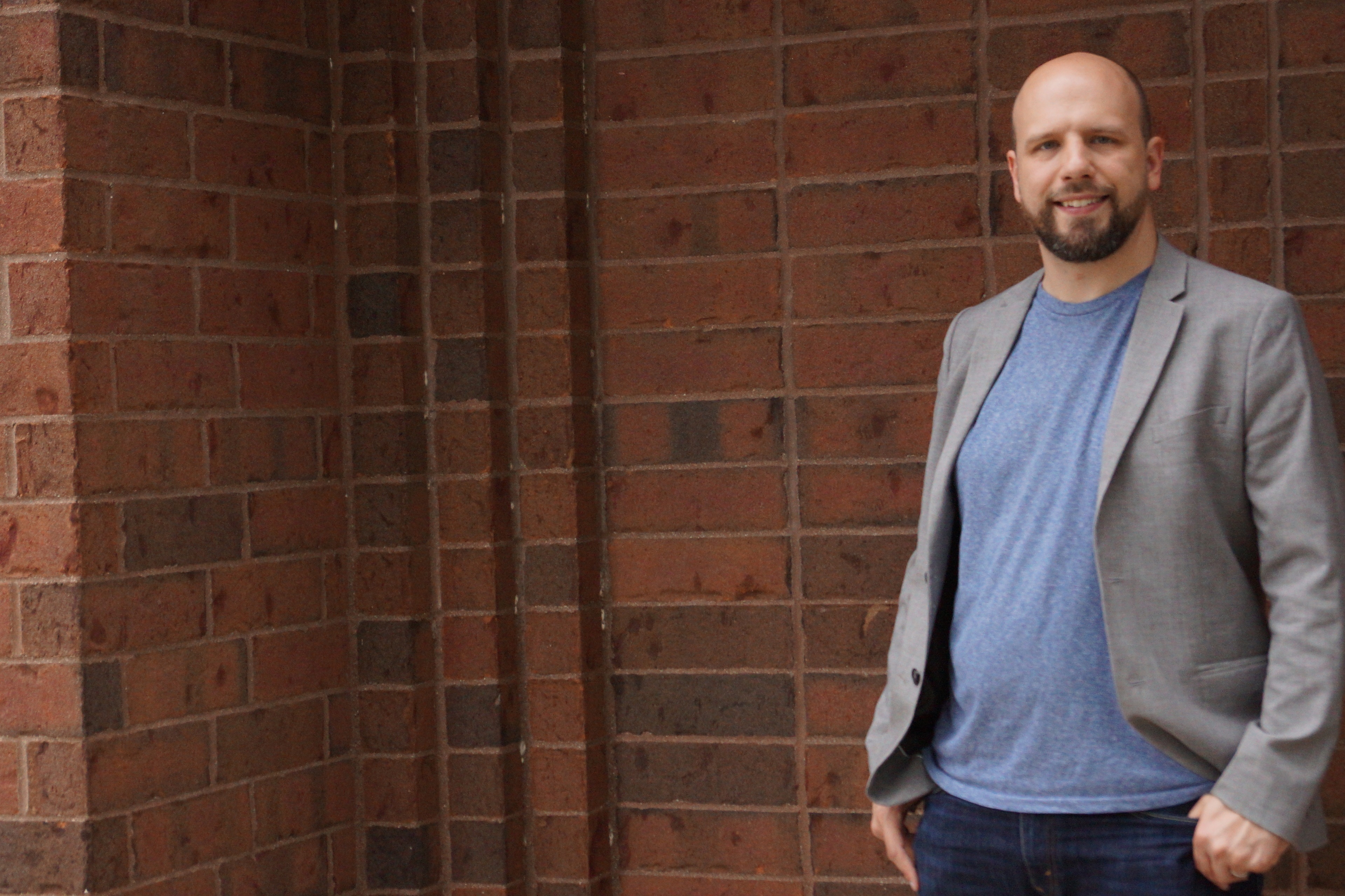 A man standing in front of a brick wall