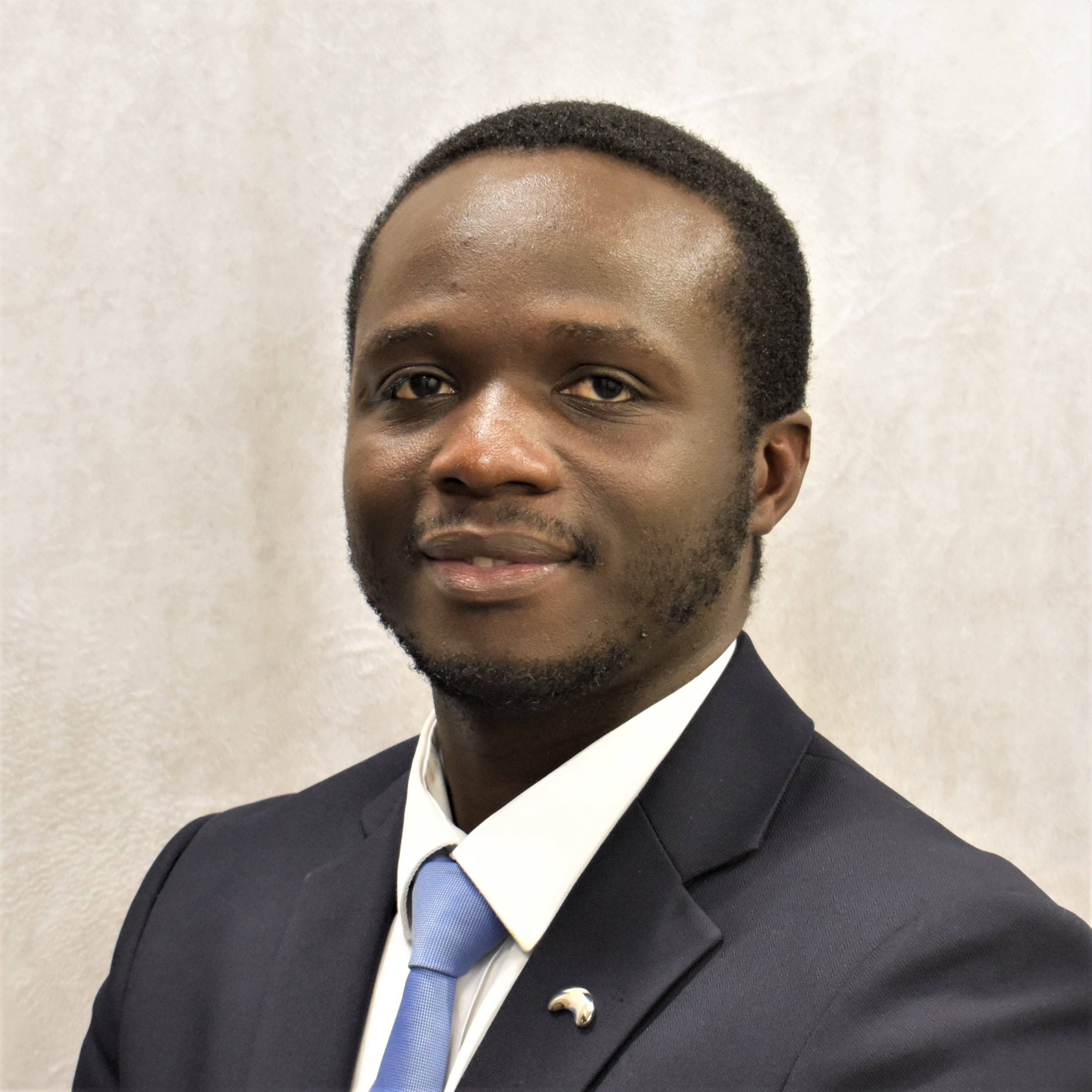 JaNai' James, in an orange blazer, in front of beige background.