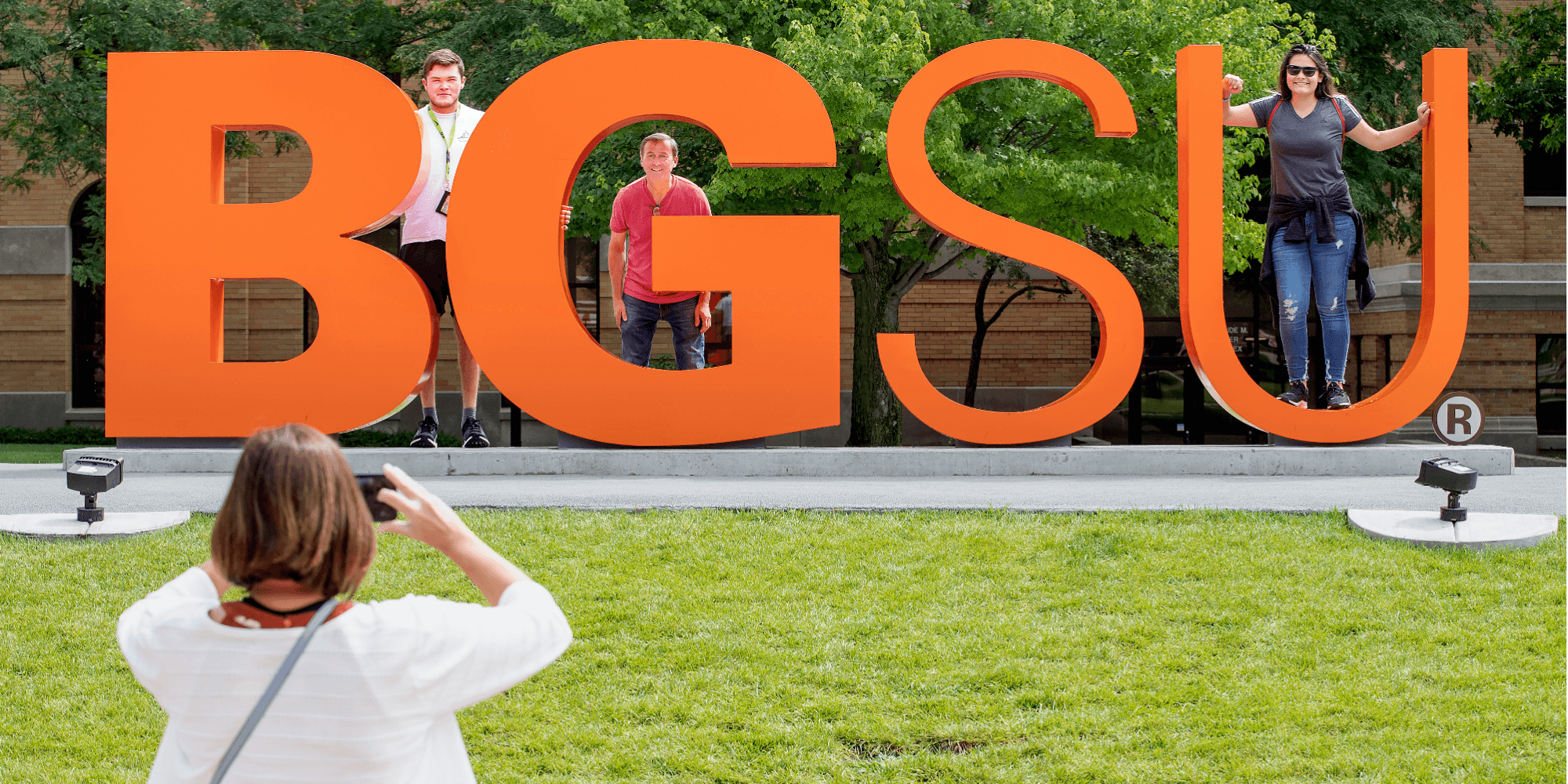 A family posing by the BGSU letters