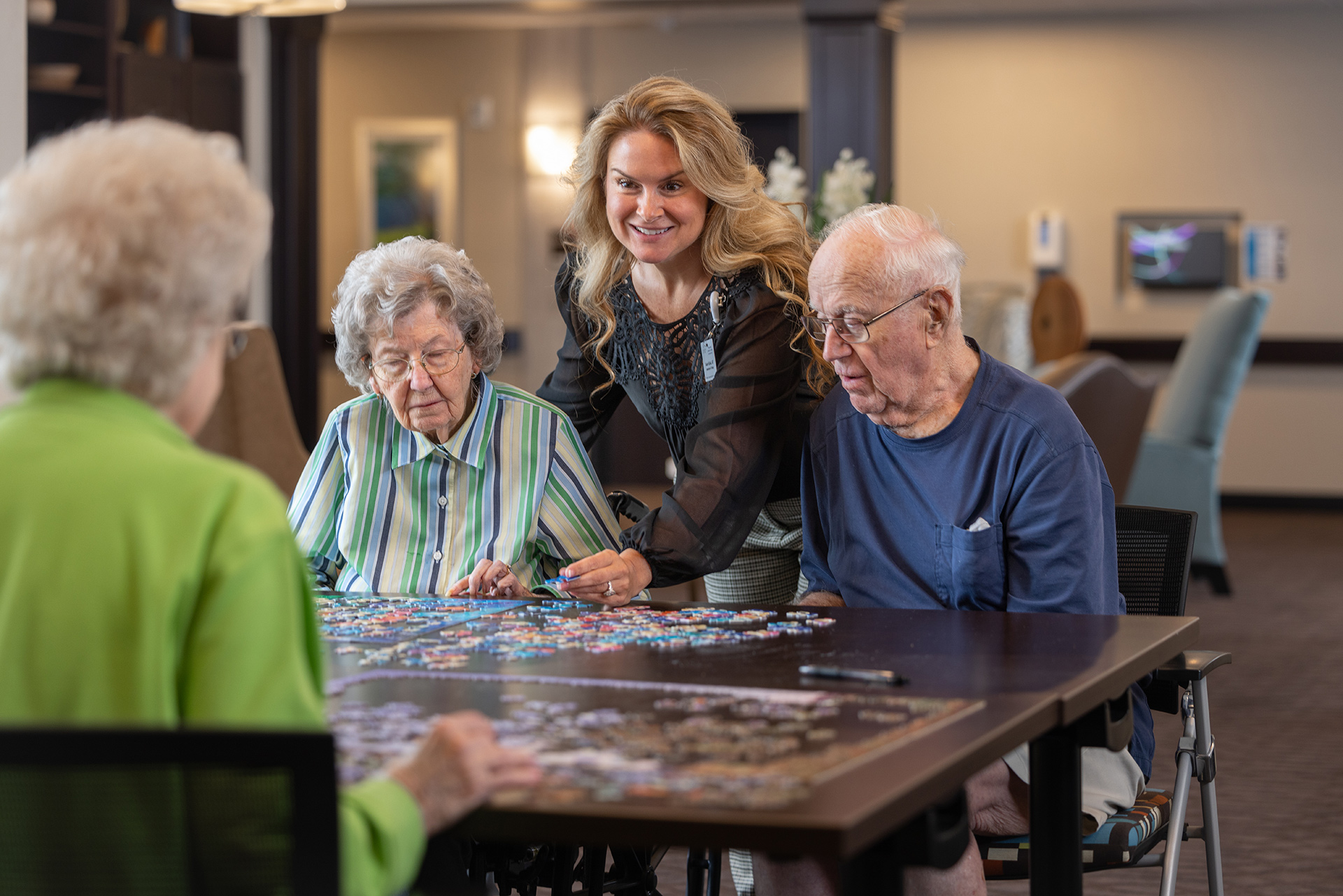 A woman works on a puzzle with a group of elderly people