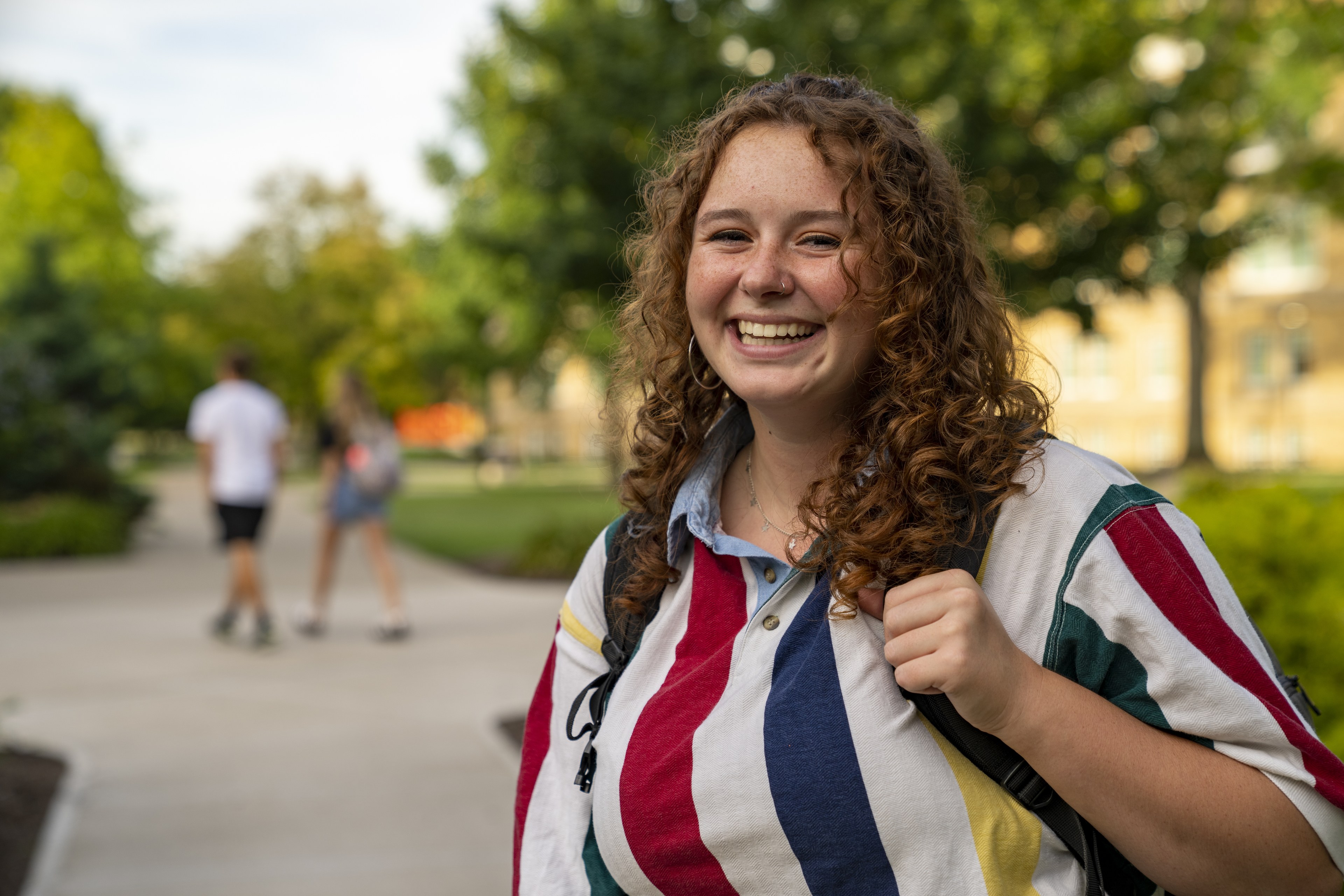 student smiling with bookbag
