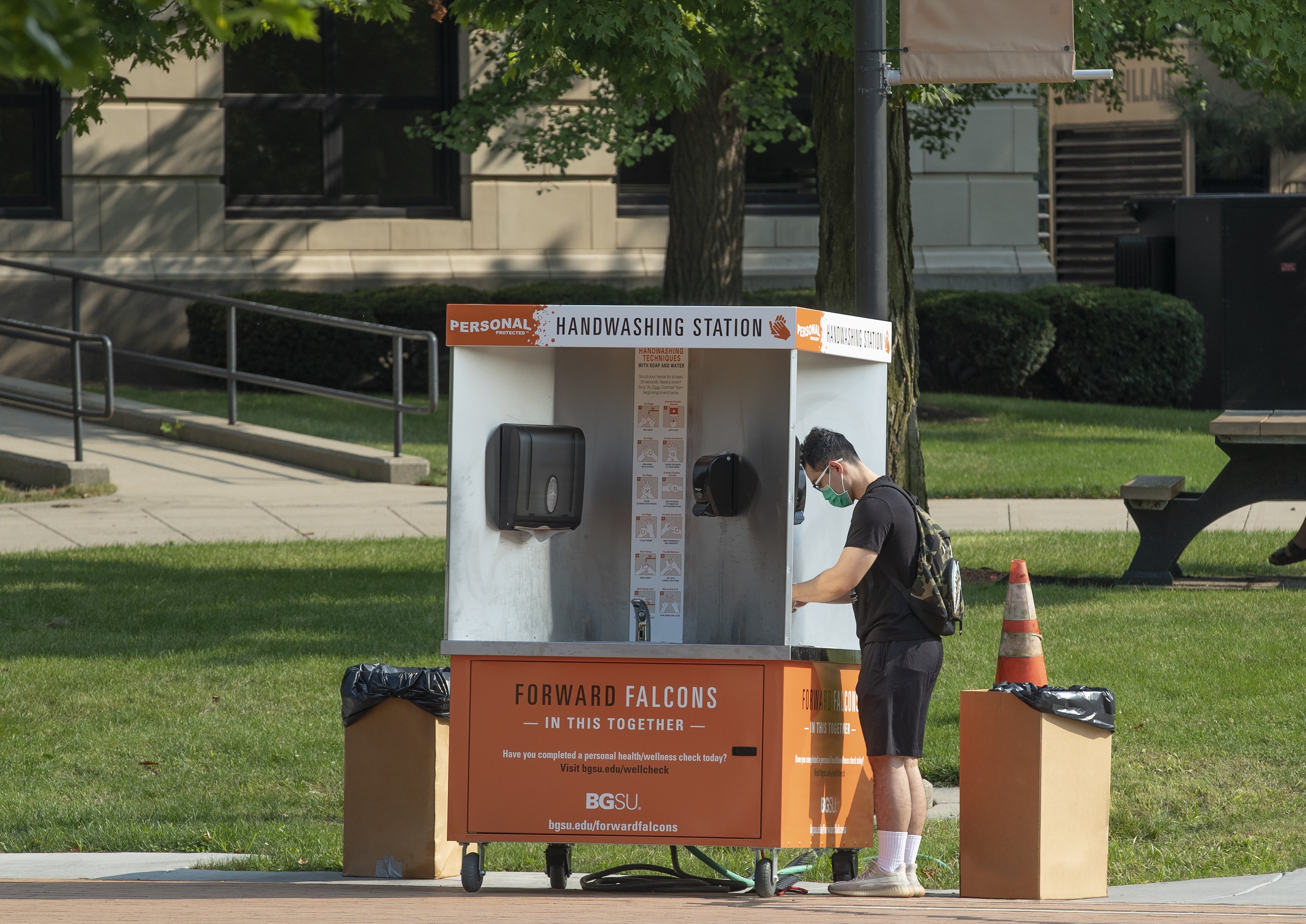 Graduate student Wenzhao Li uses a sanitizing station on campus