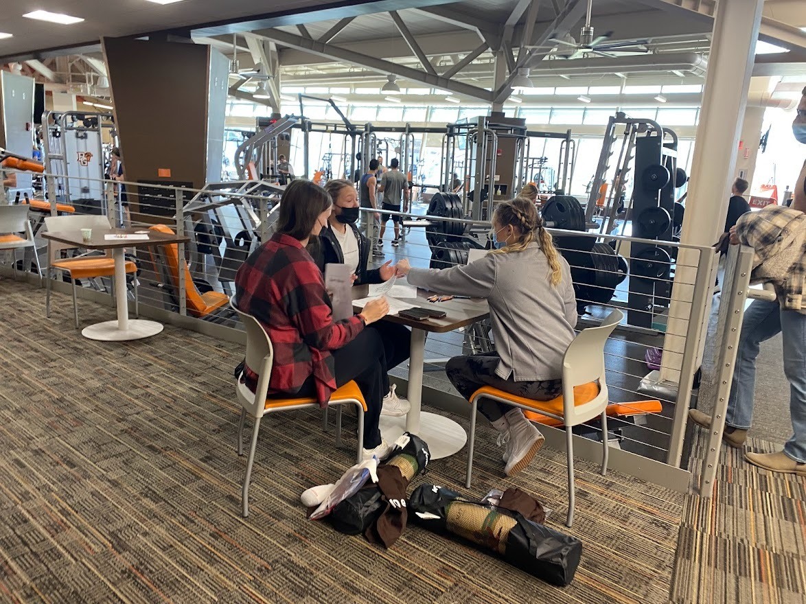 Three students sitting at a table, coloring.