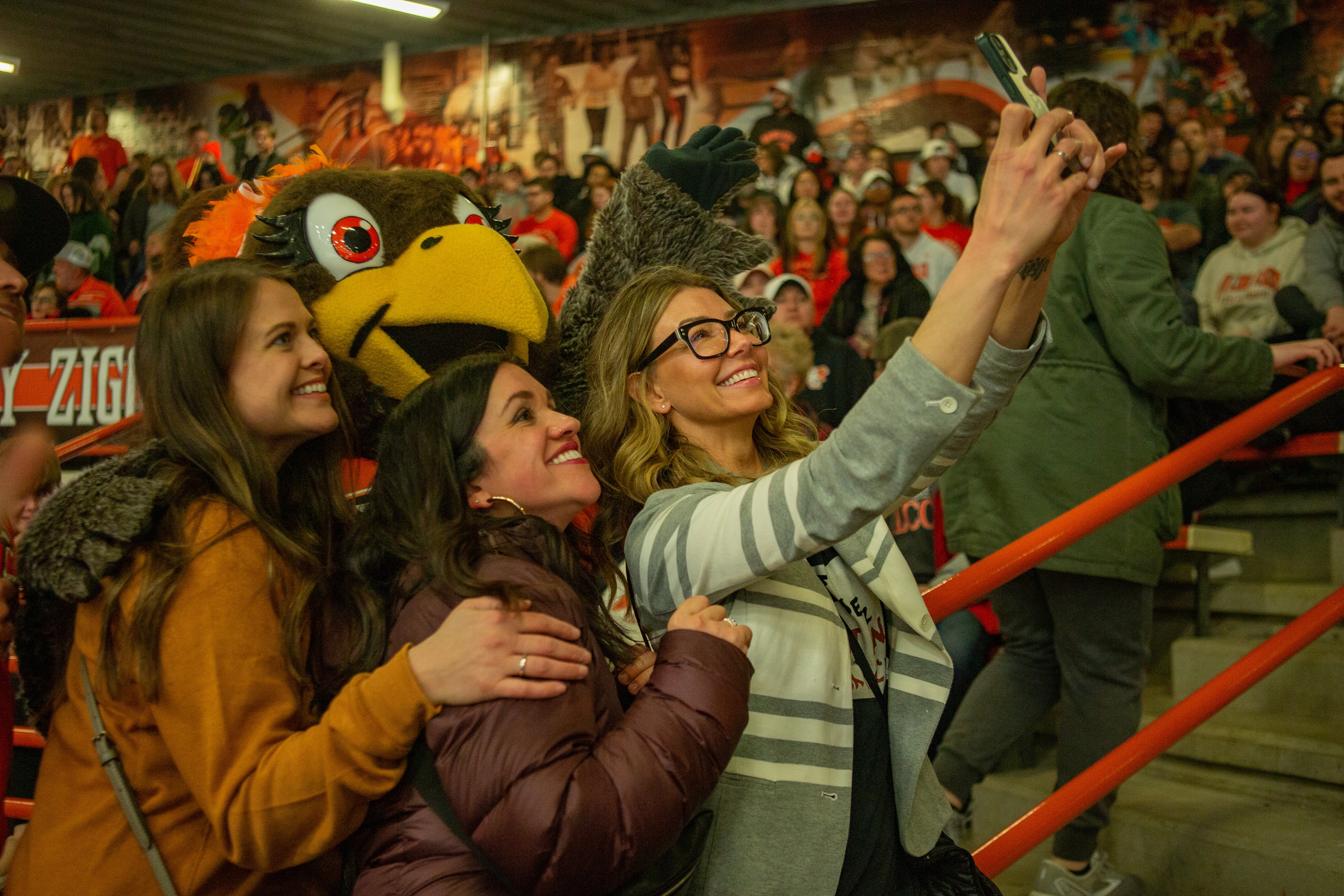 BGSU mascot Frieda Falcon takes photo with three fan