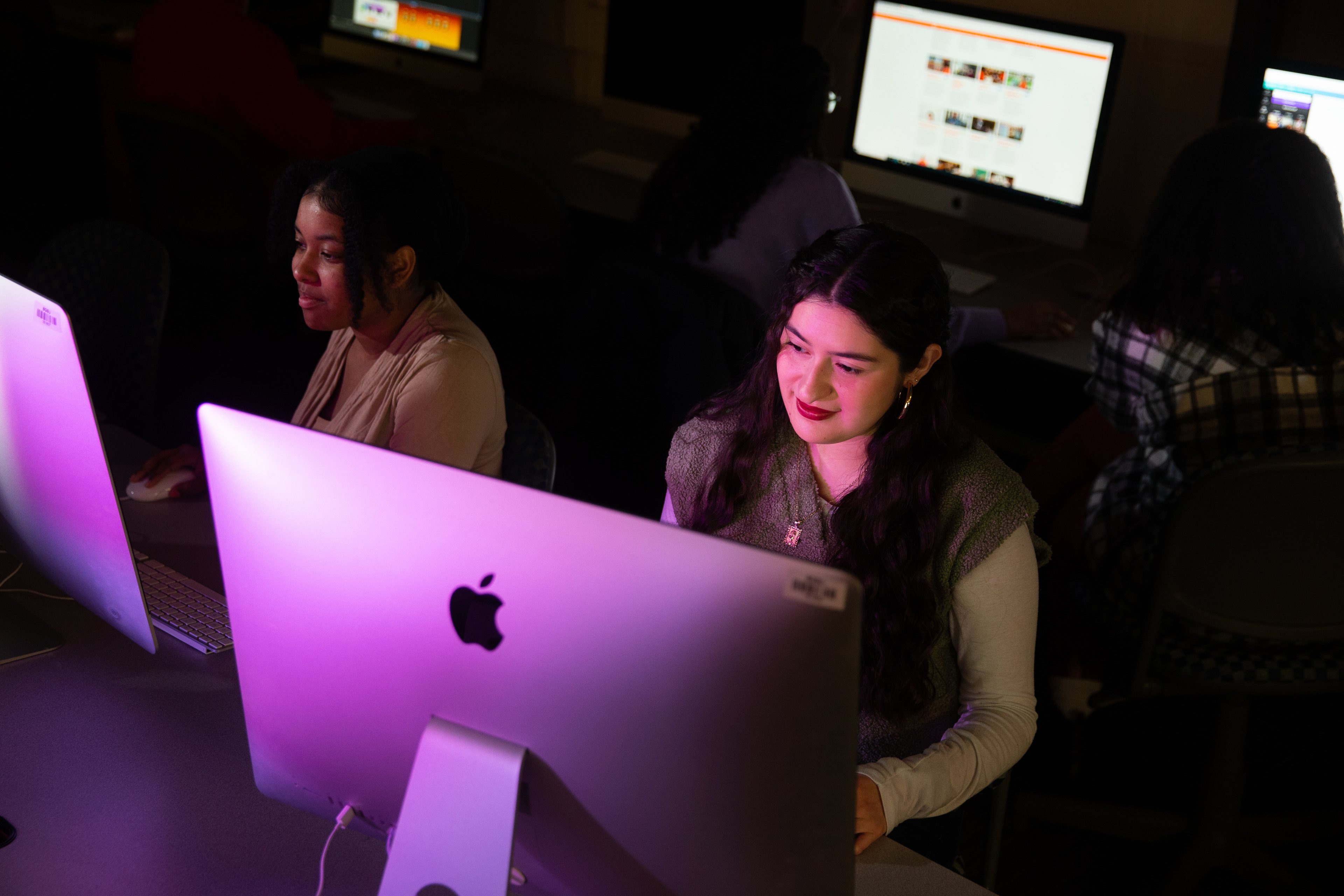 Two people look at a computer screen in a dark room.