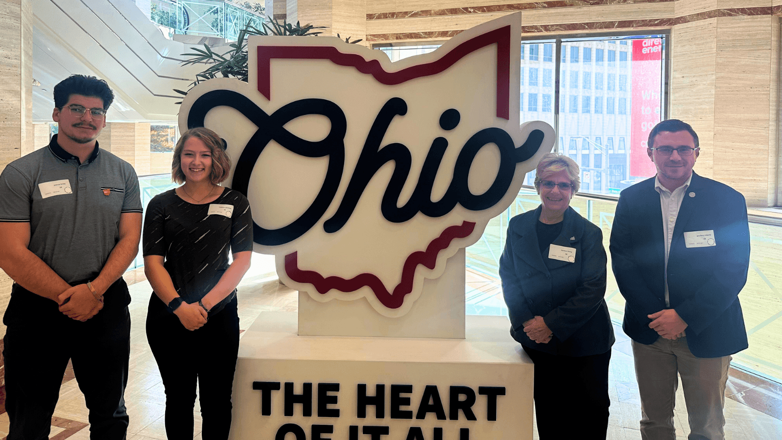 Four BGSU representatives stand in front of a sculpture of the state of Ohio