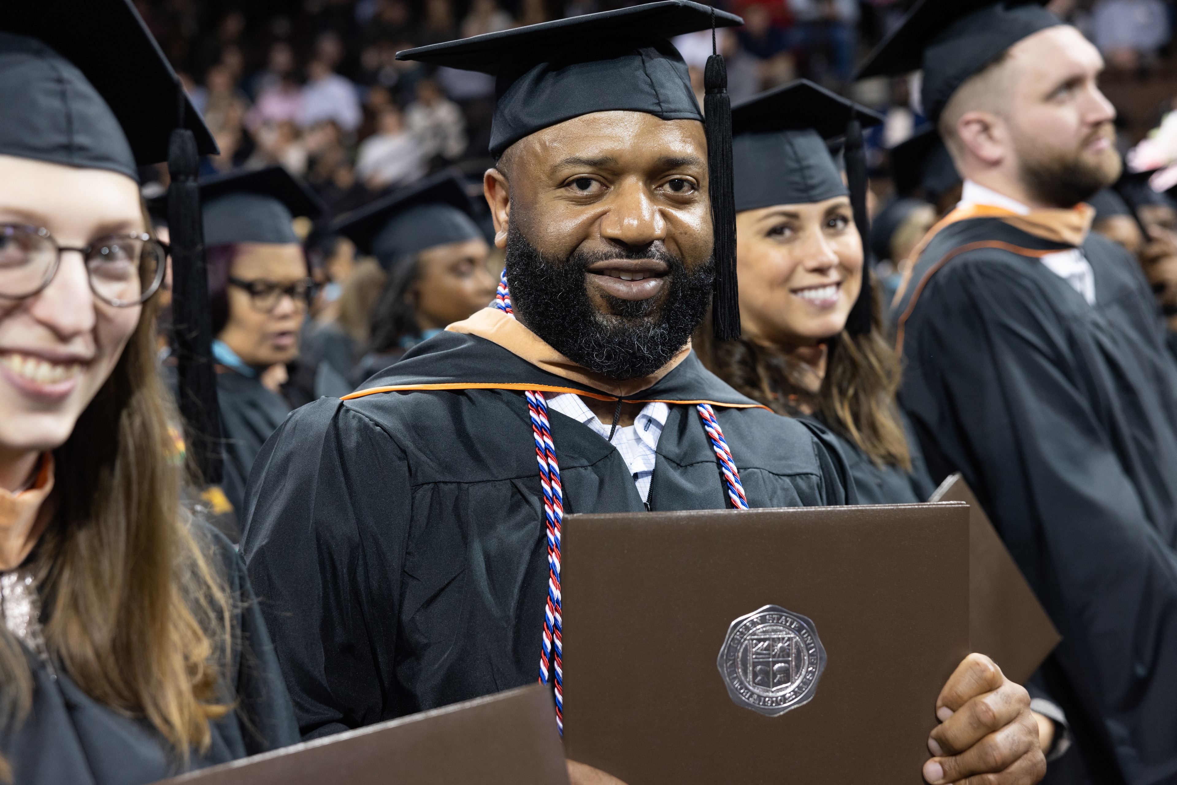 Three graduates smile while seated at Commencement