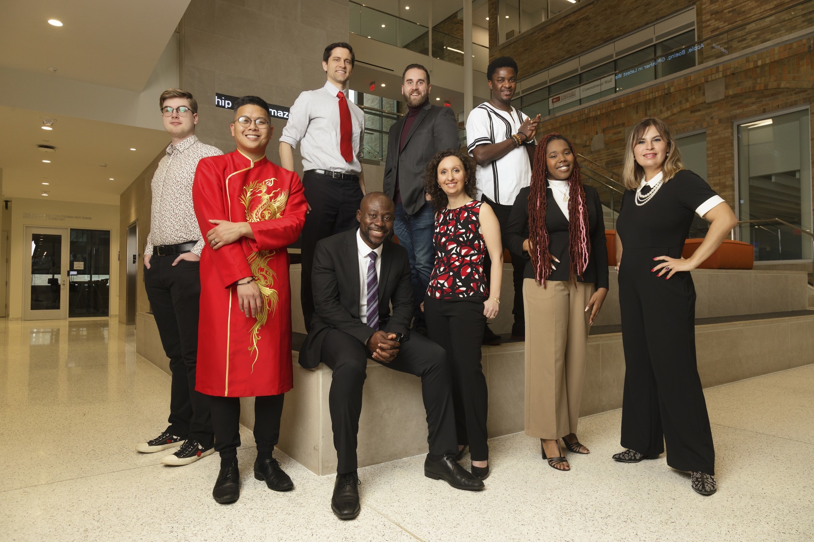9 people pose, sitting and standing, inside a building at BGSU