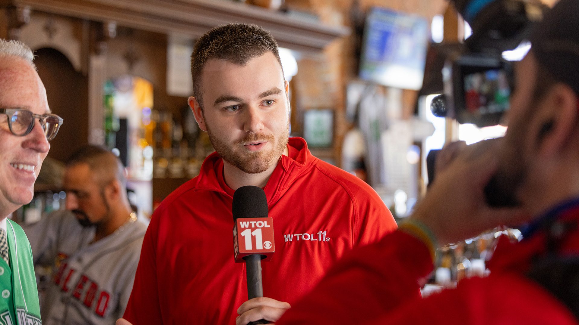 A journalist with a microphone interviews a person while a camera person records