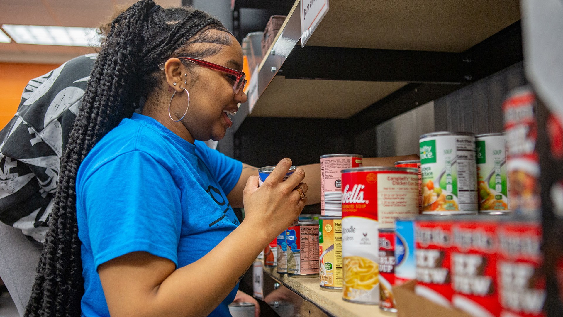 A person puts canned goods on a shelf