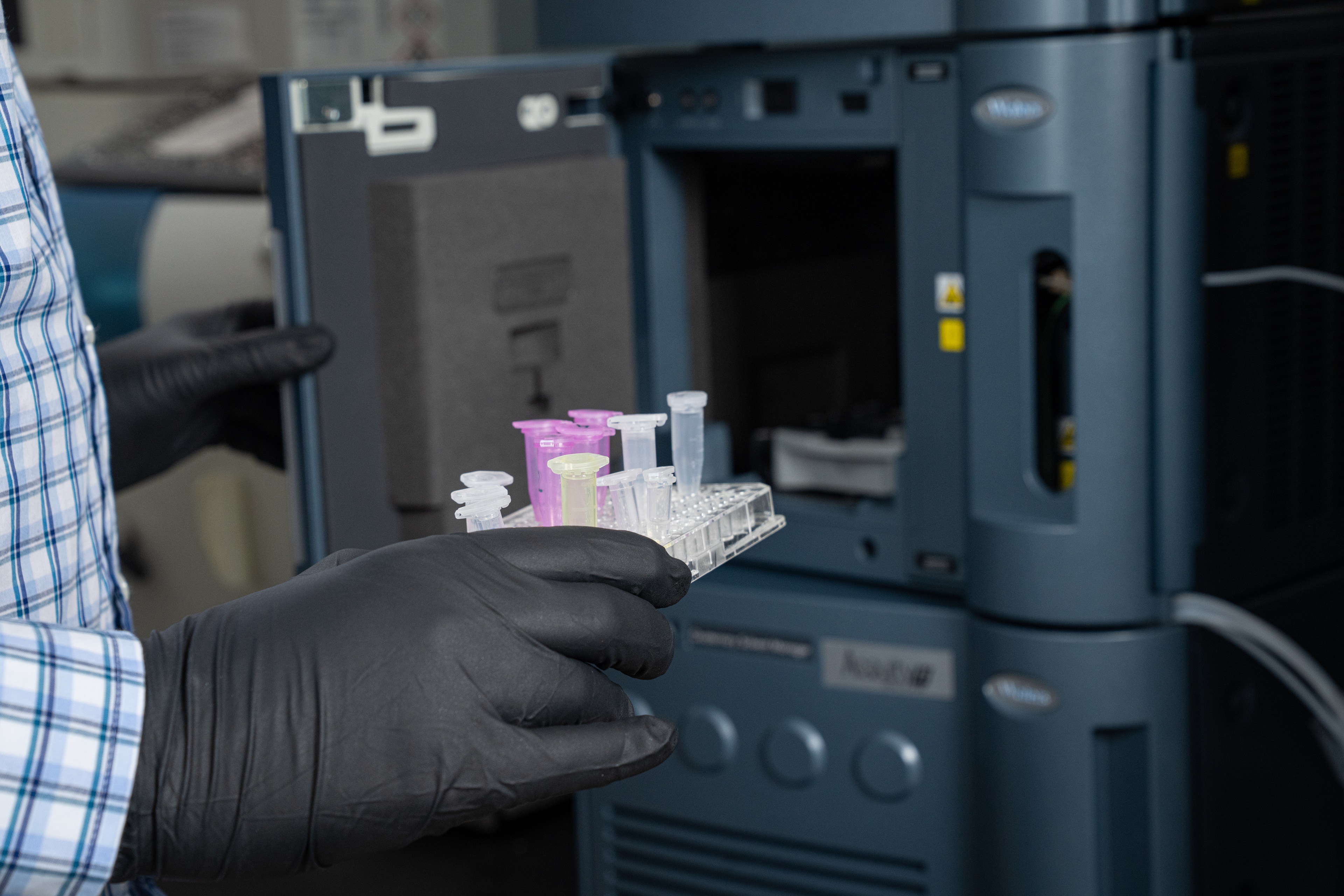 A scientist holds a container of vials.