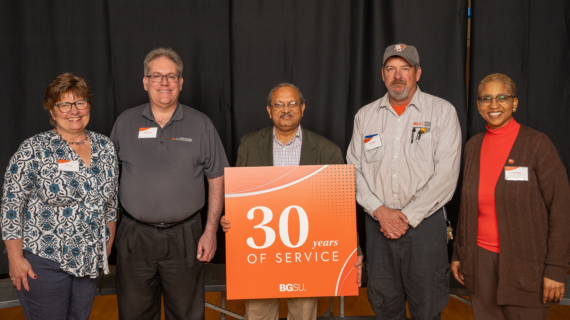 A group of people stands with a 30-year work anniversary sign