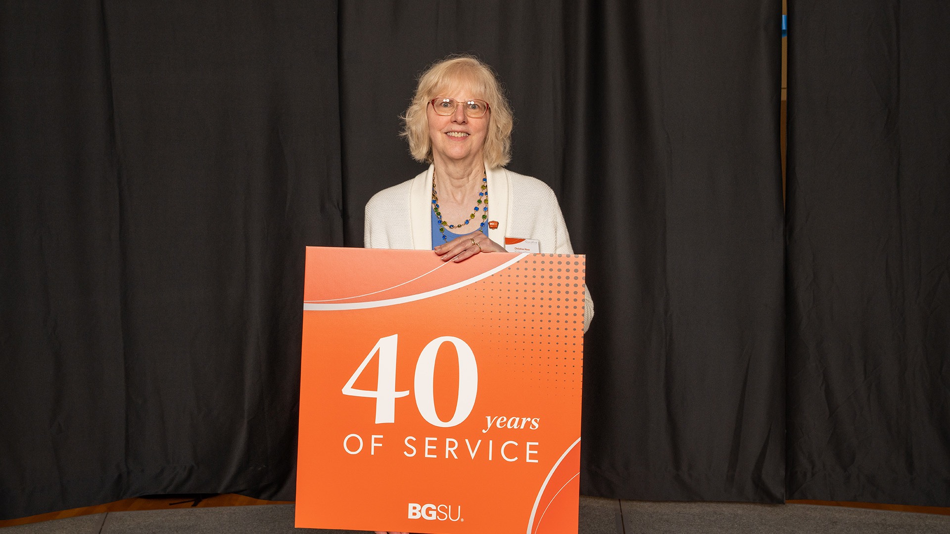 A person stands with a 40-year work anniversary sign