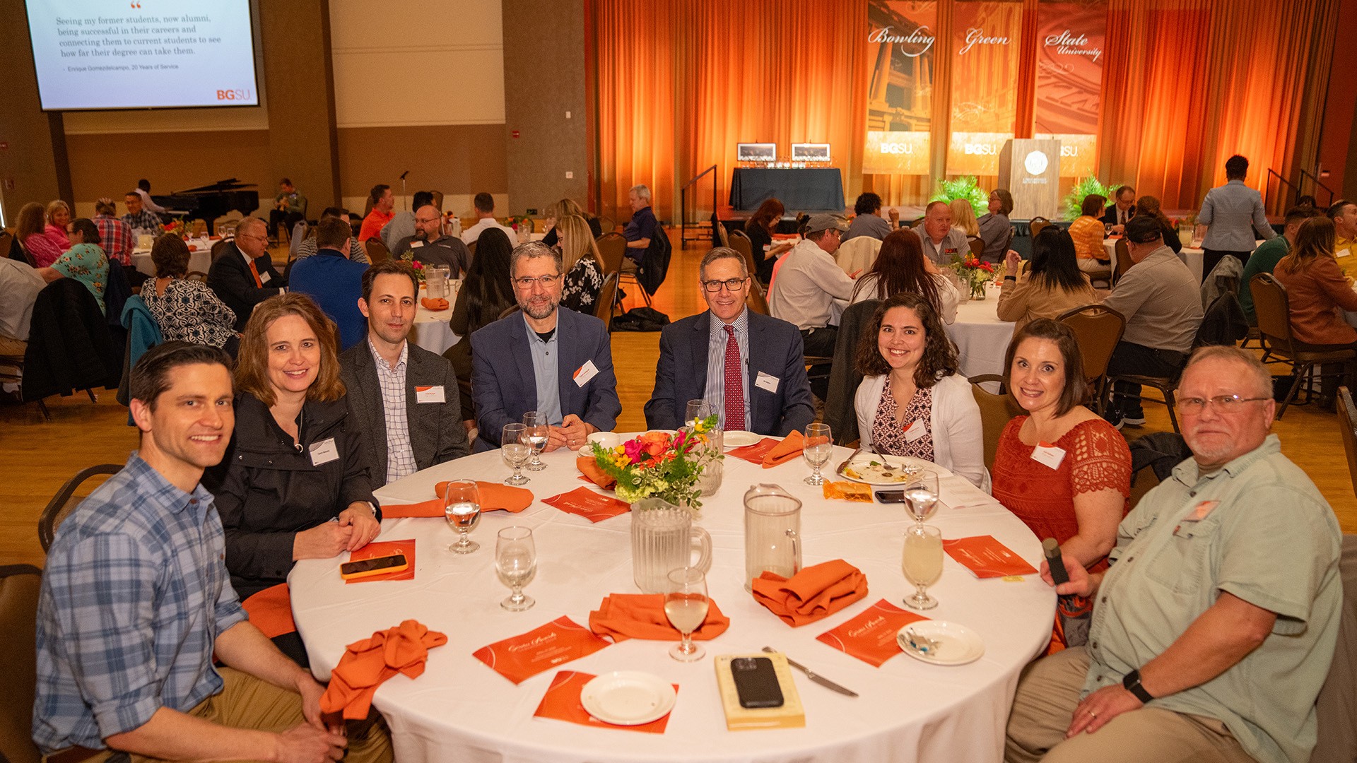 A group of people sits at a round table in a ballroom