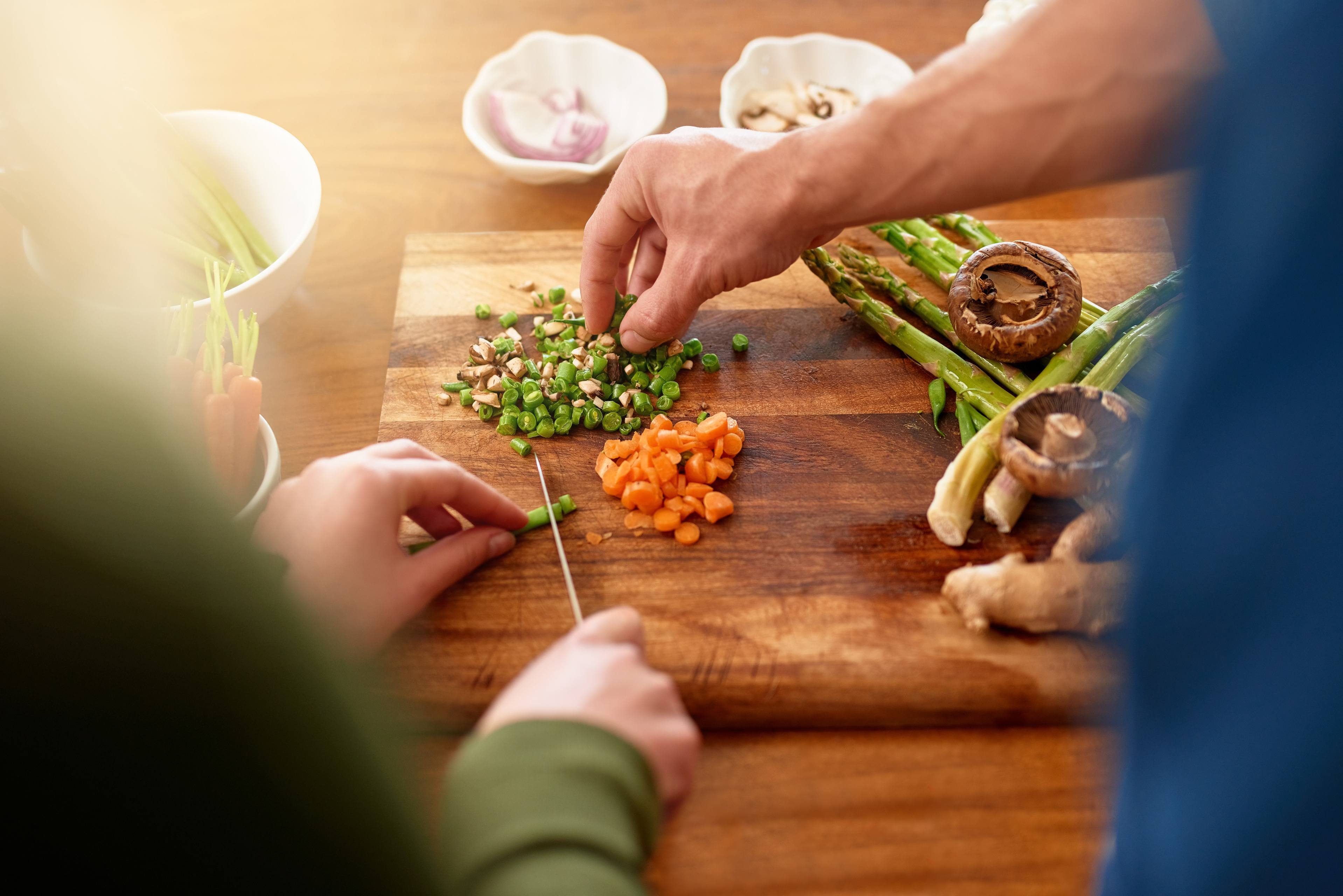 Hand reaches to grab vegetables off cutting board