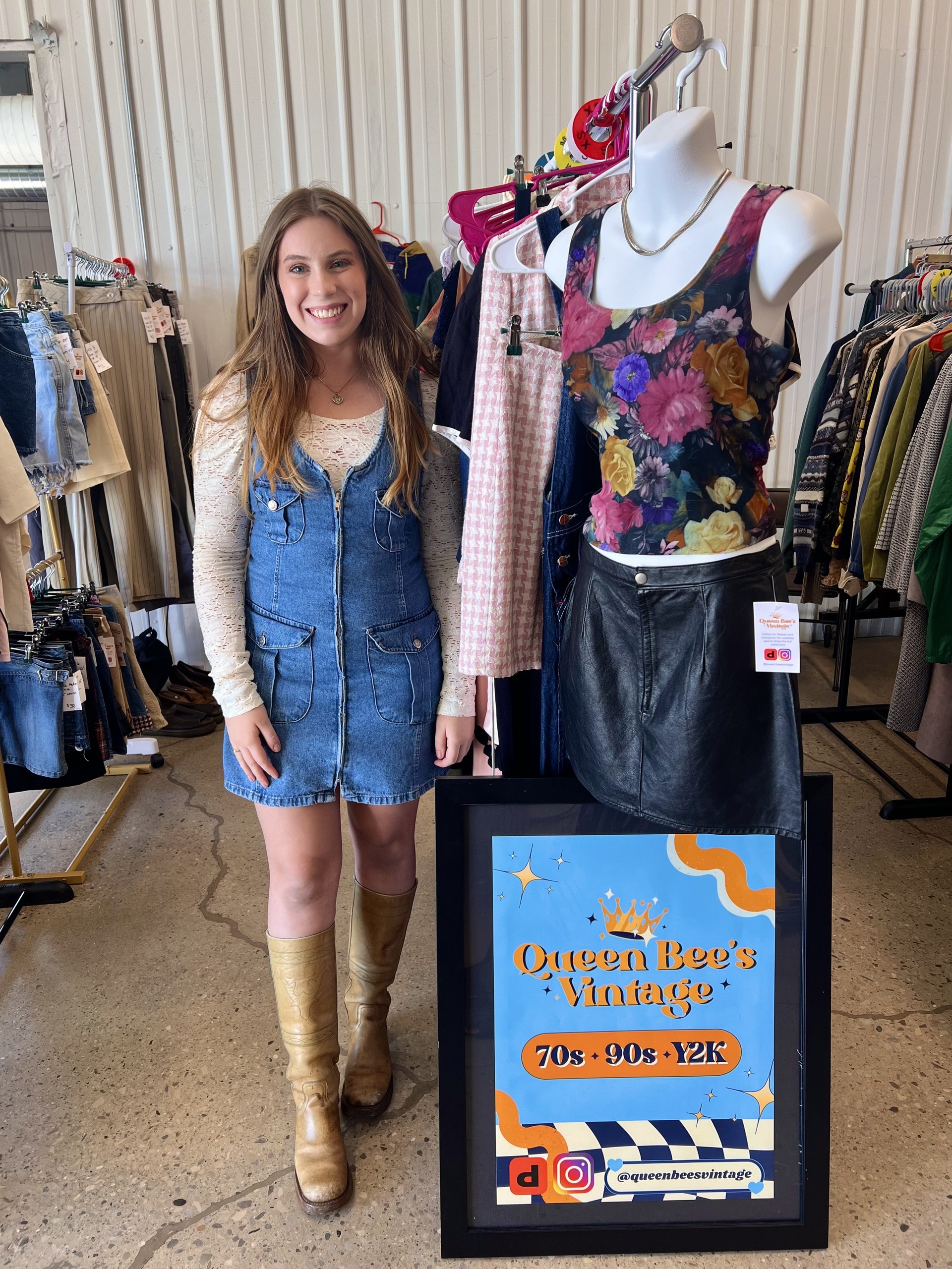 A woman stands in front of a clothing rack.