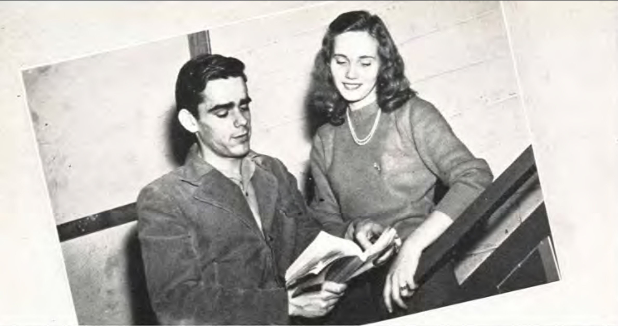 A young man and a young woman look through a book together