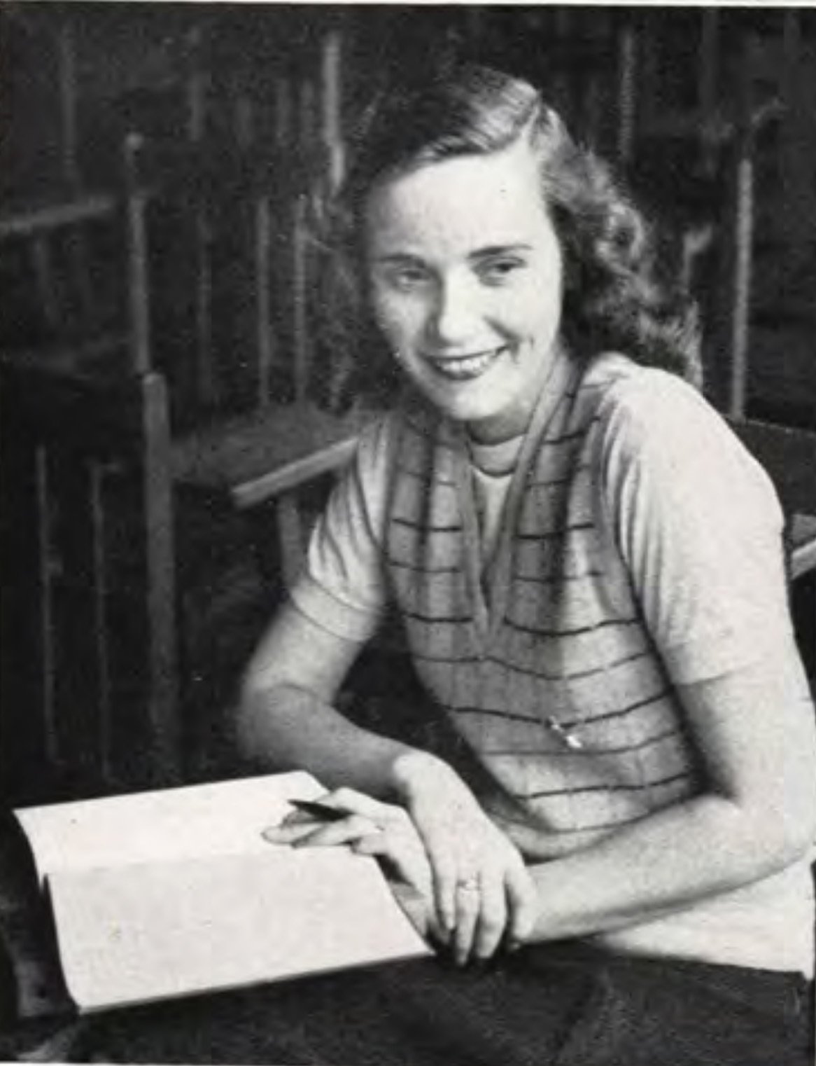 A black and white photo of a young woman with a book 