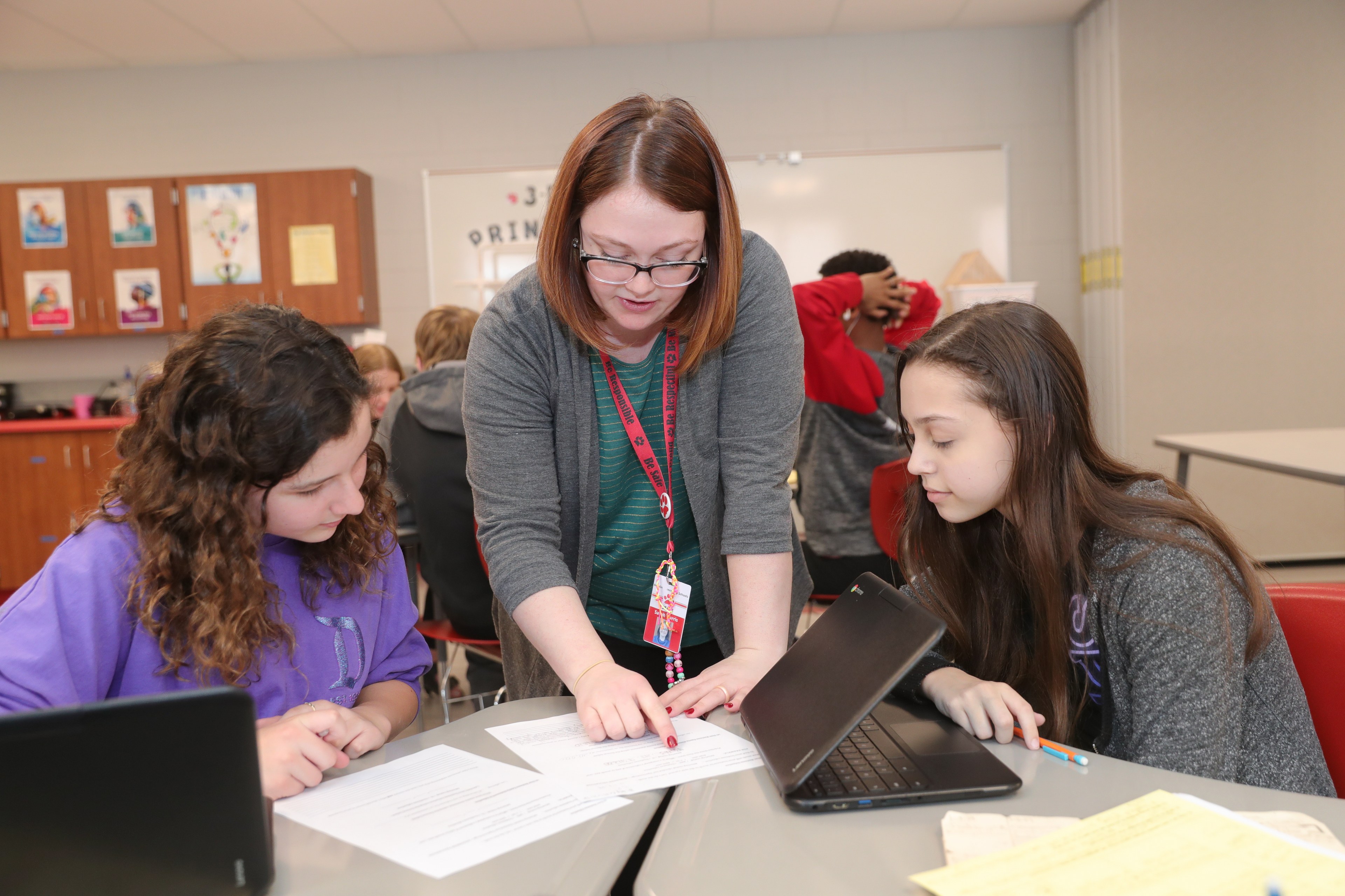 Teacher working with two students in a classroom