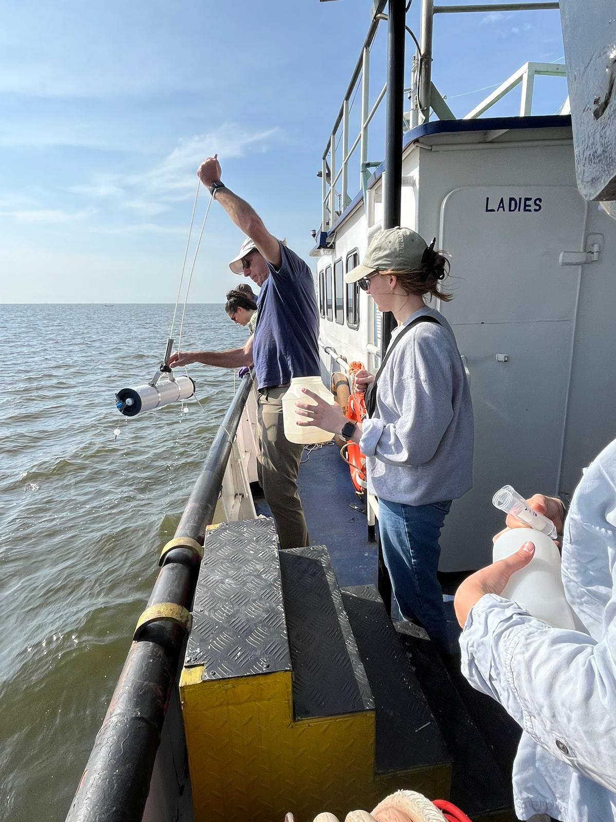 A man pulls water samples off the side of boat