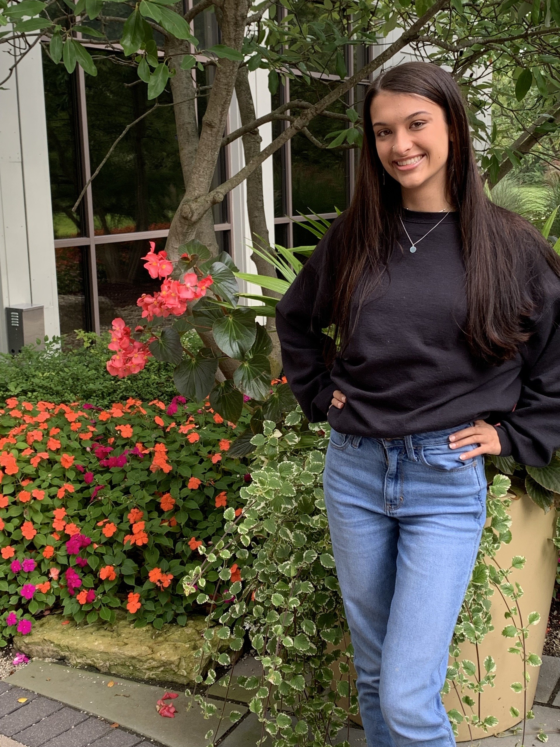 Young woman stands next to a display of brightly colored flowers 