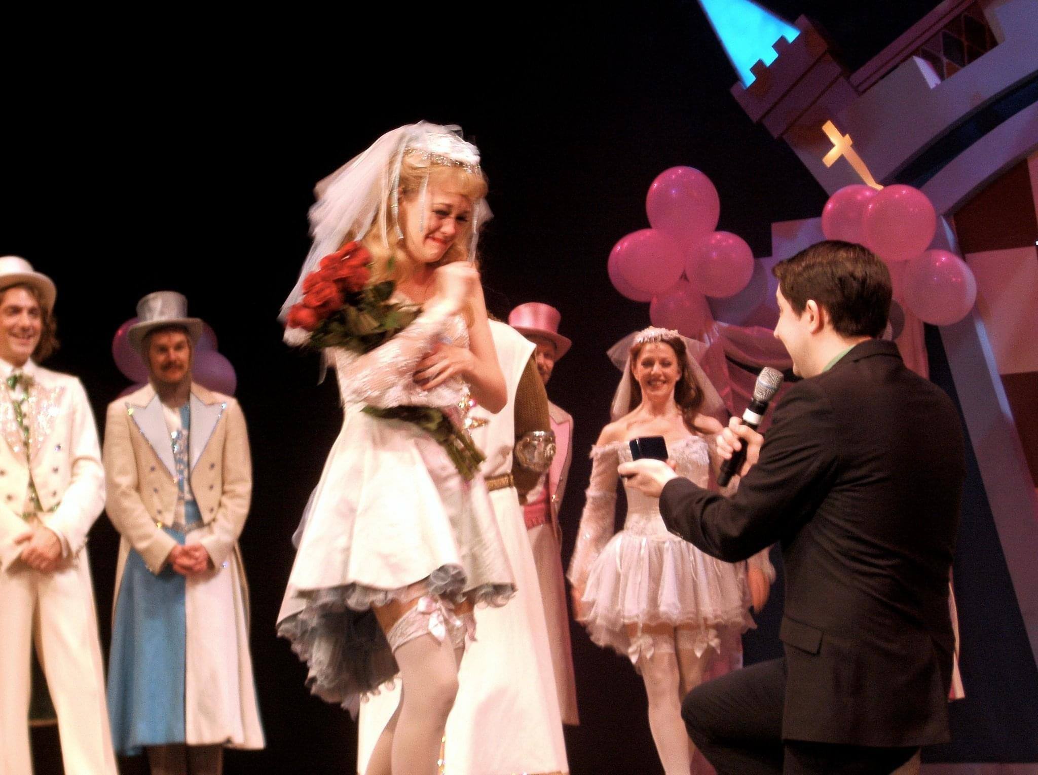 A person down on one knee proposes to another person. 