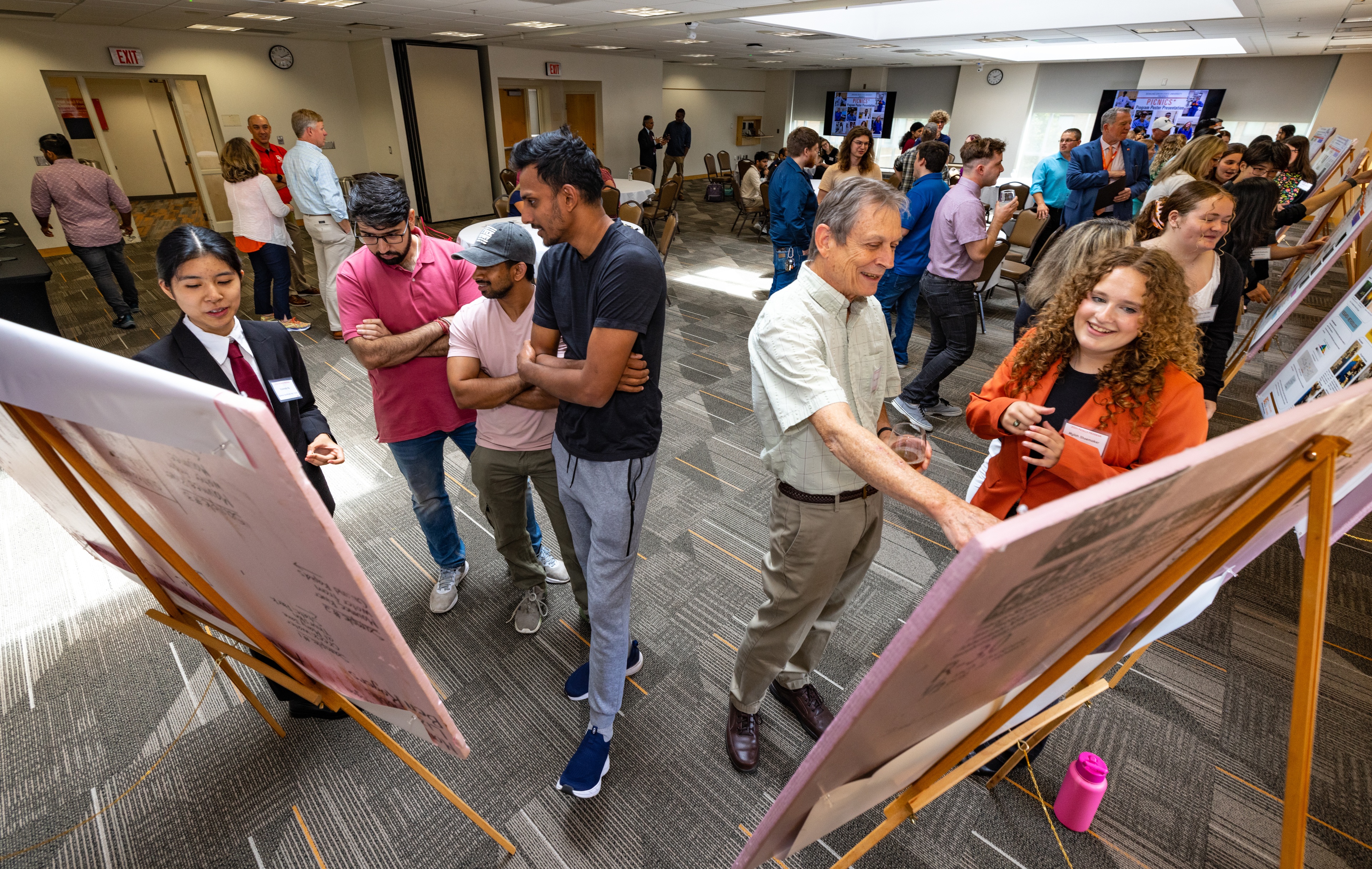 Wide-angle shot of high school students presenting their research posters 