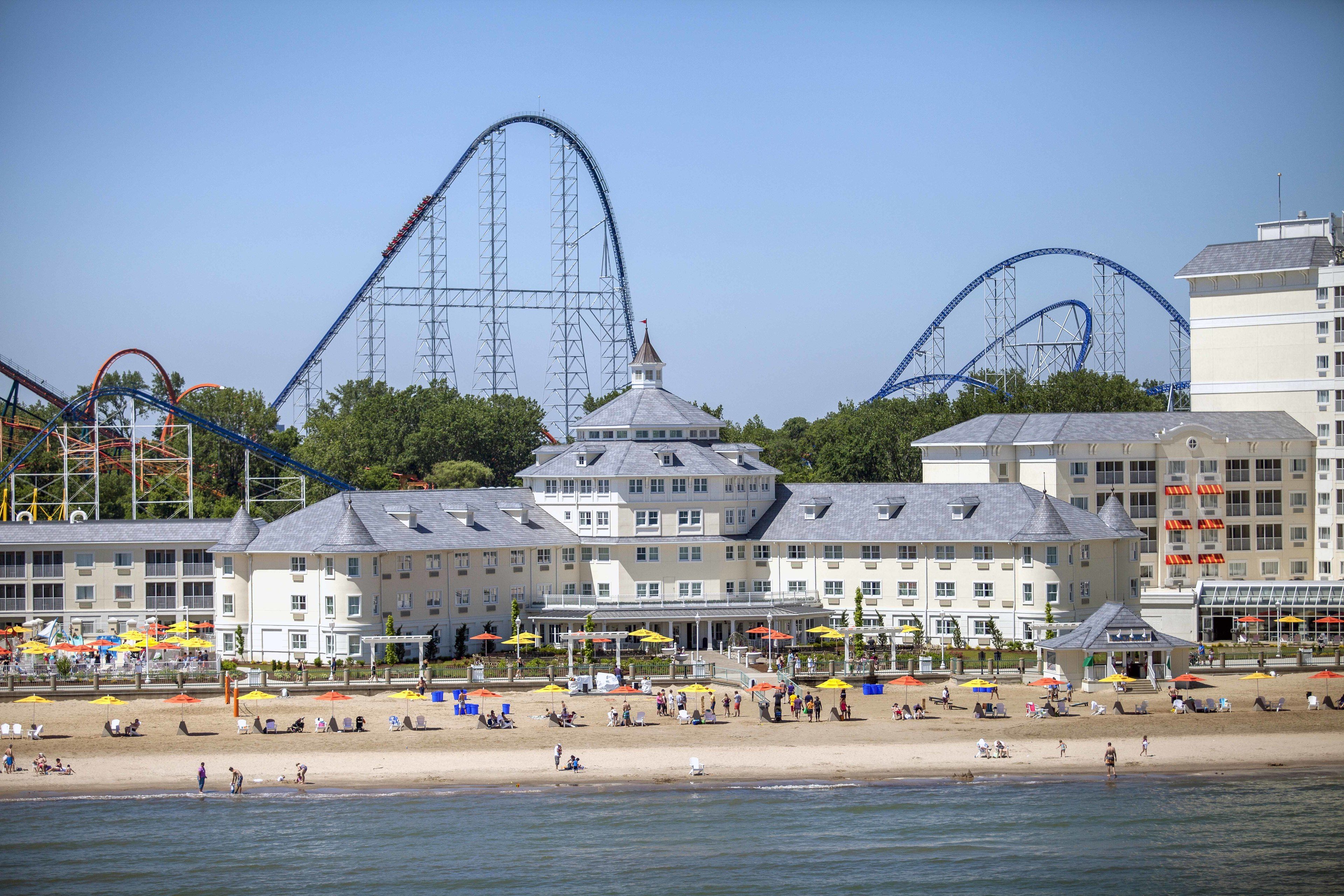 Amusement park in the background of a hotel located on a beach.