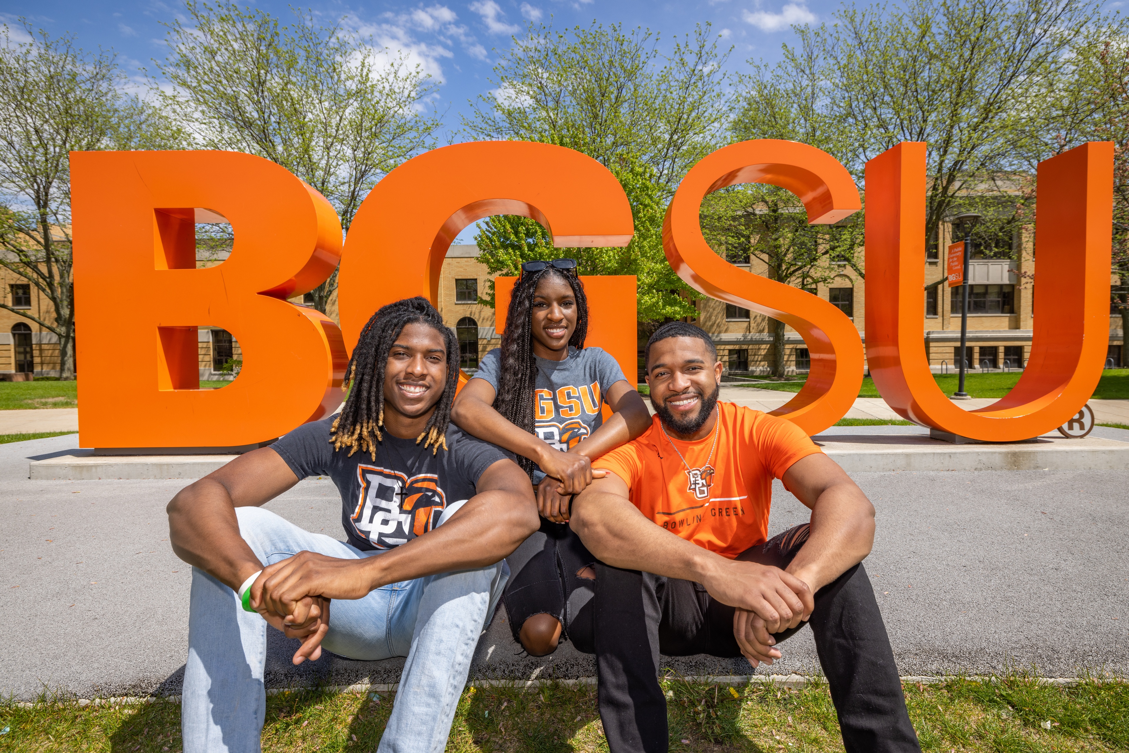 Three people smiling in front of the BGSU letters