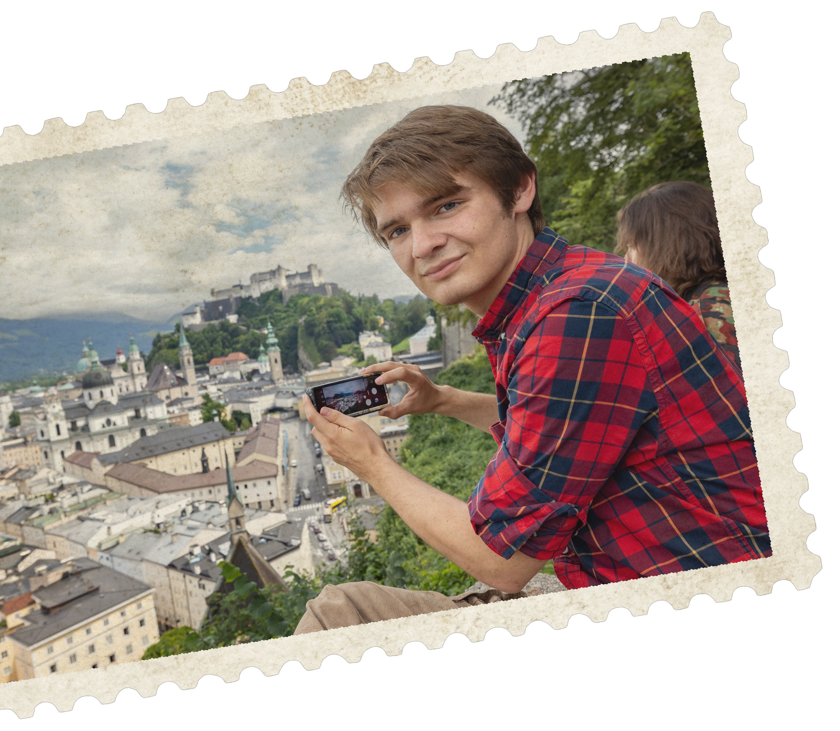 A young man takes a photo of a view of rooftops in Salzburg, Austria 