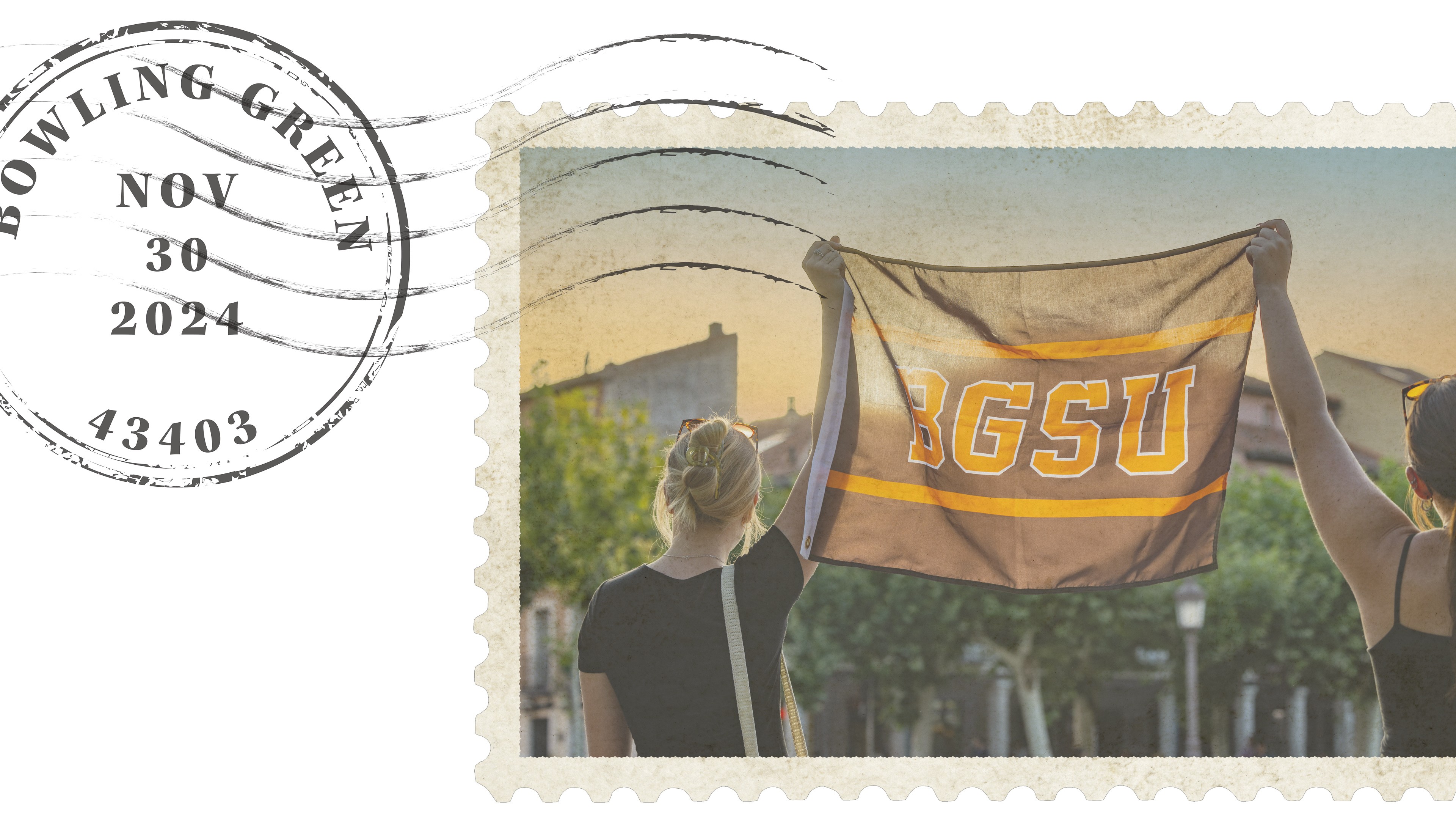 Two students hold a BGSU flag in the air