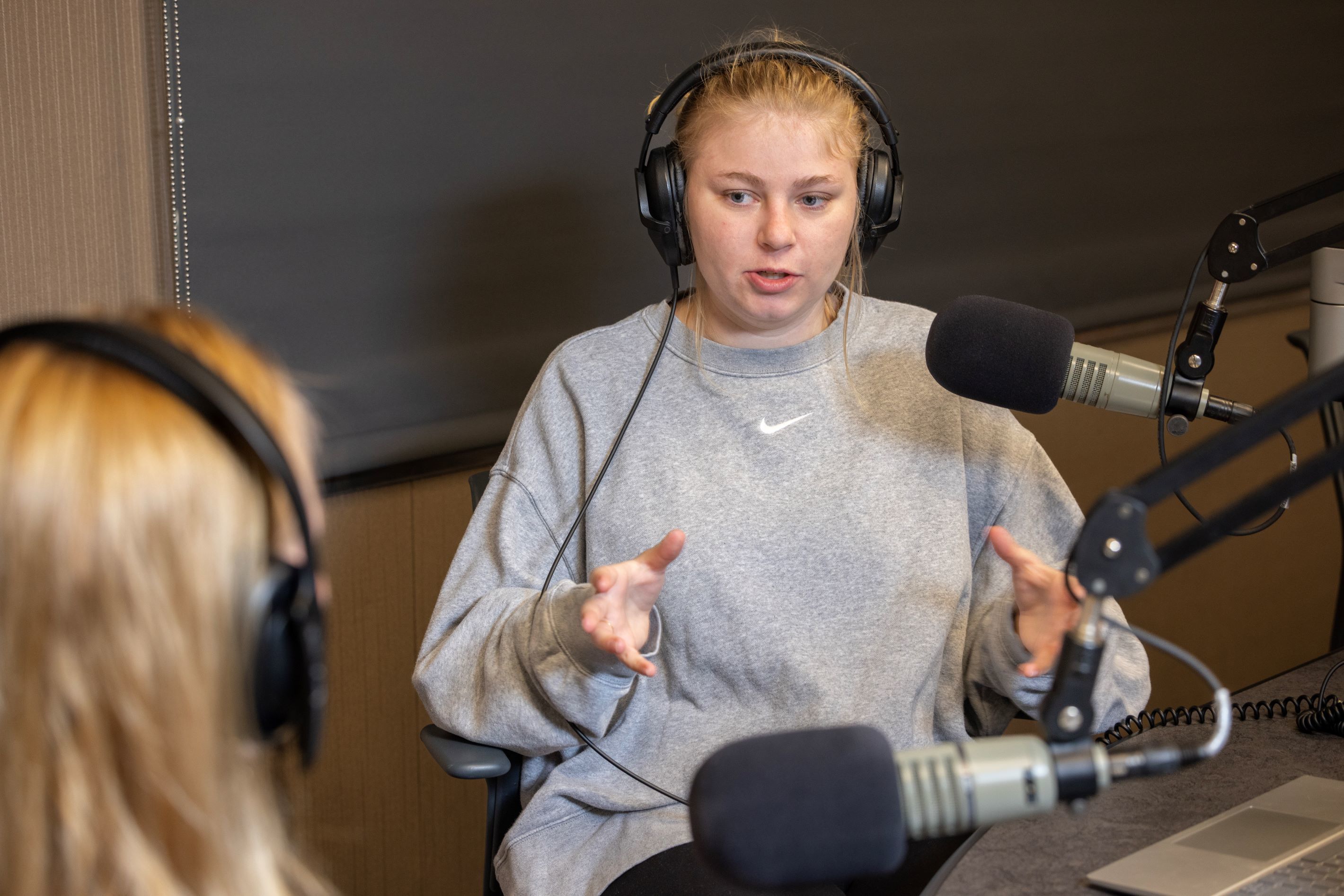 A student sits with headphones on while talking into a microphone