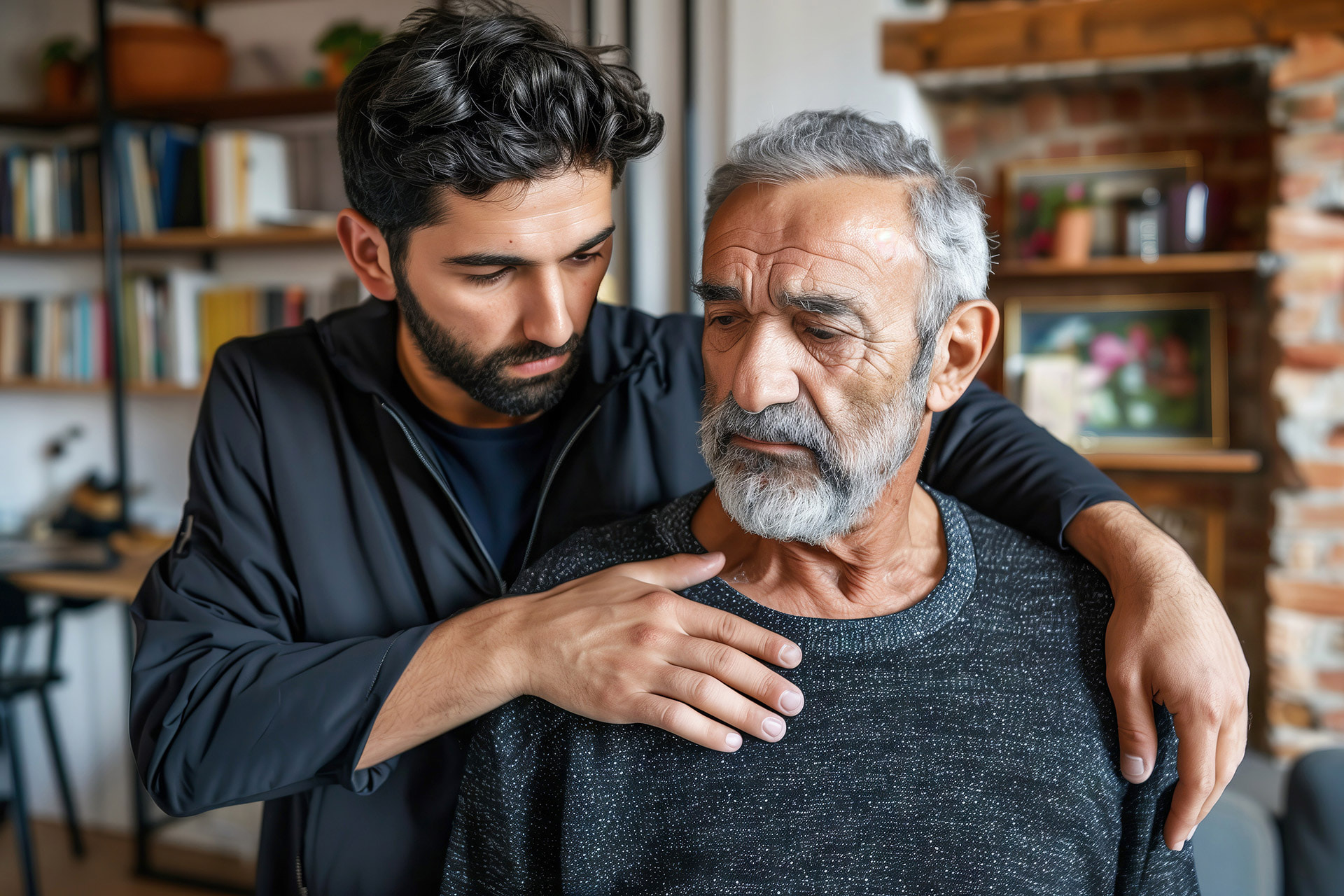 An adult male comforts his elderly father