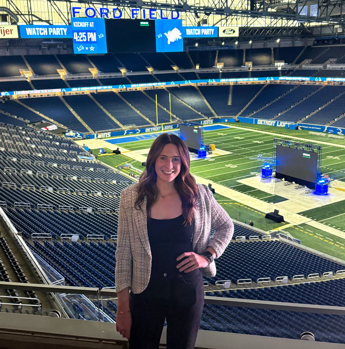 A woman poses for a photo inside a football stadium.