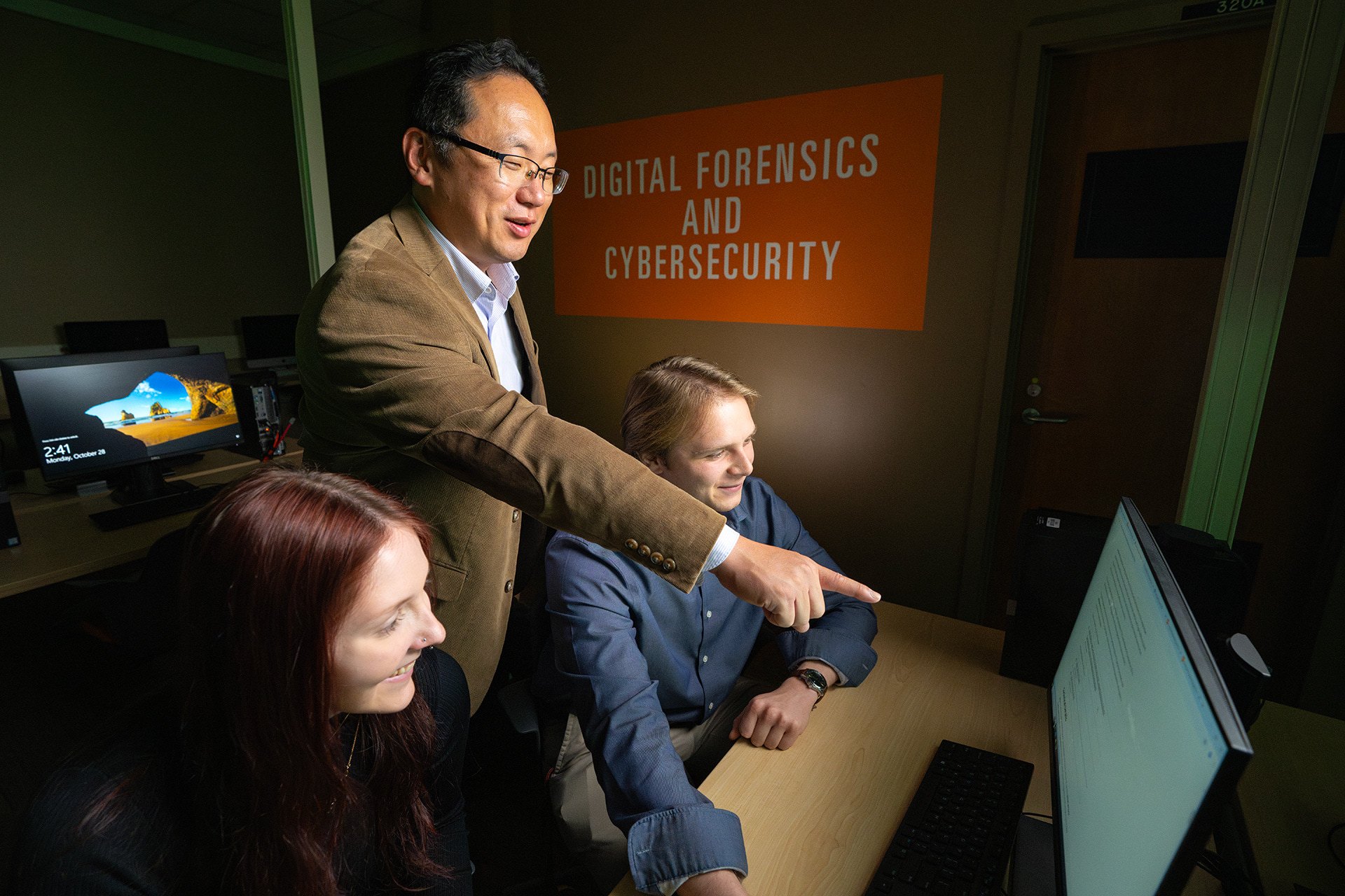 A professor and two students look at a computer screen
