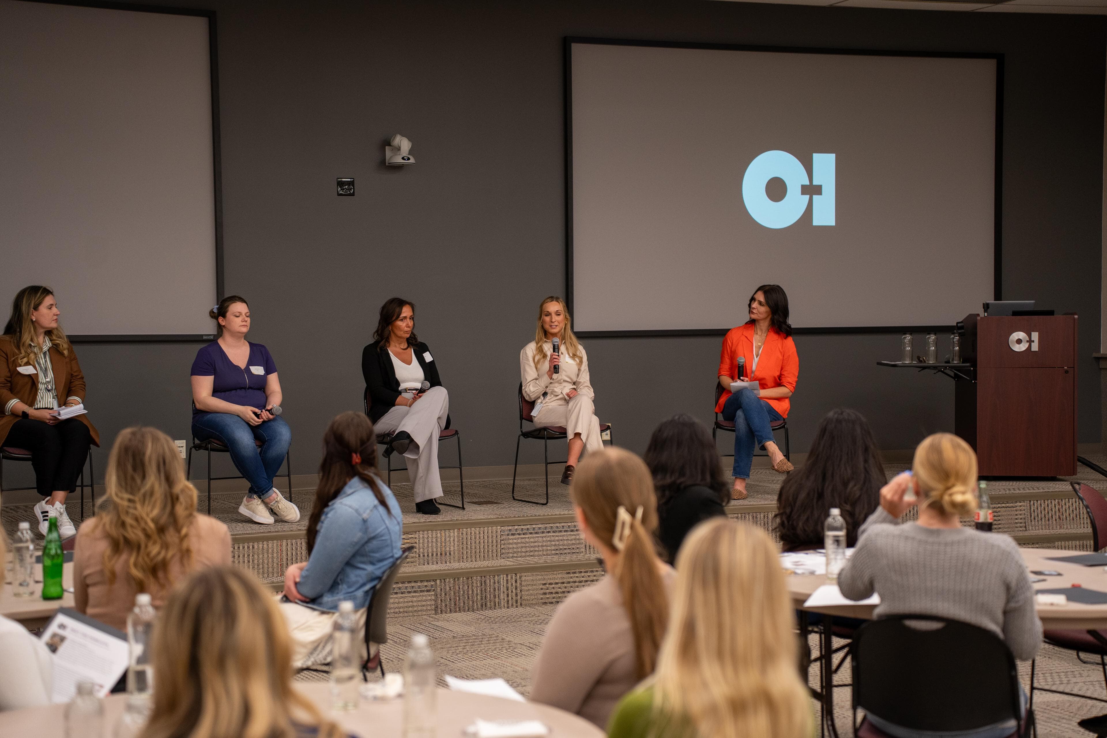 A panel presents to a full room of participants. 