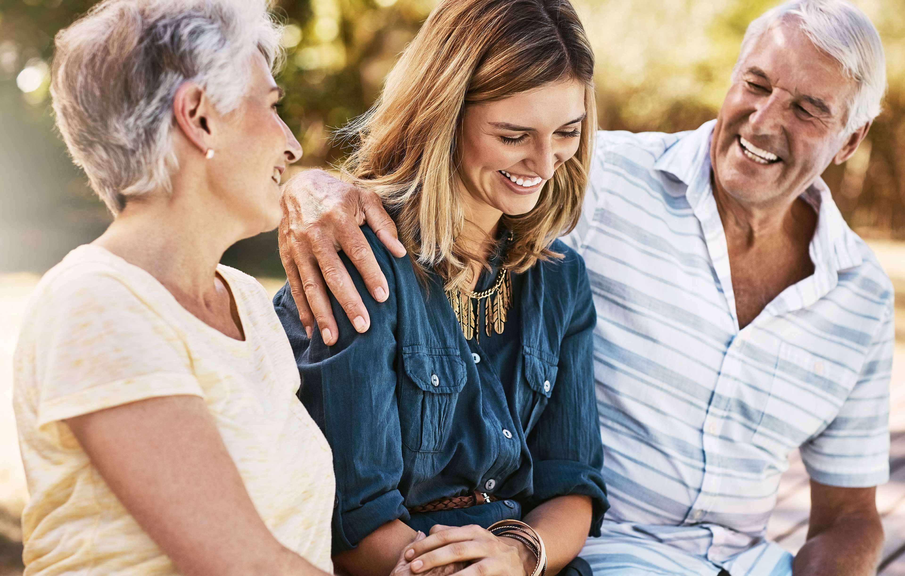 An adult daughter sits between her mom and dad