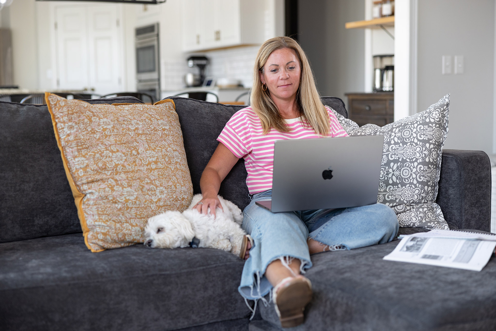 A person sits on a couch with a laptop