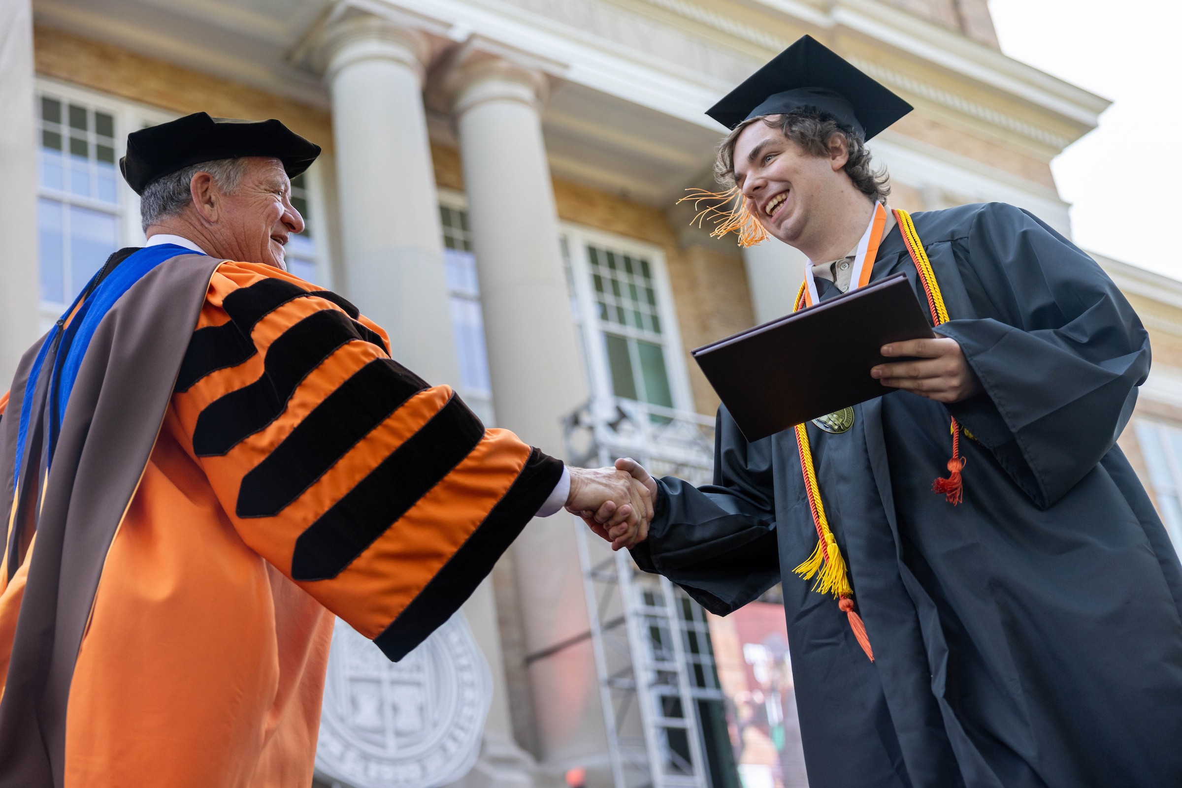 A graduate shakes hands with BGSU President Rodney K. Rogers