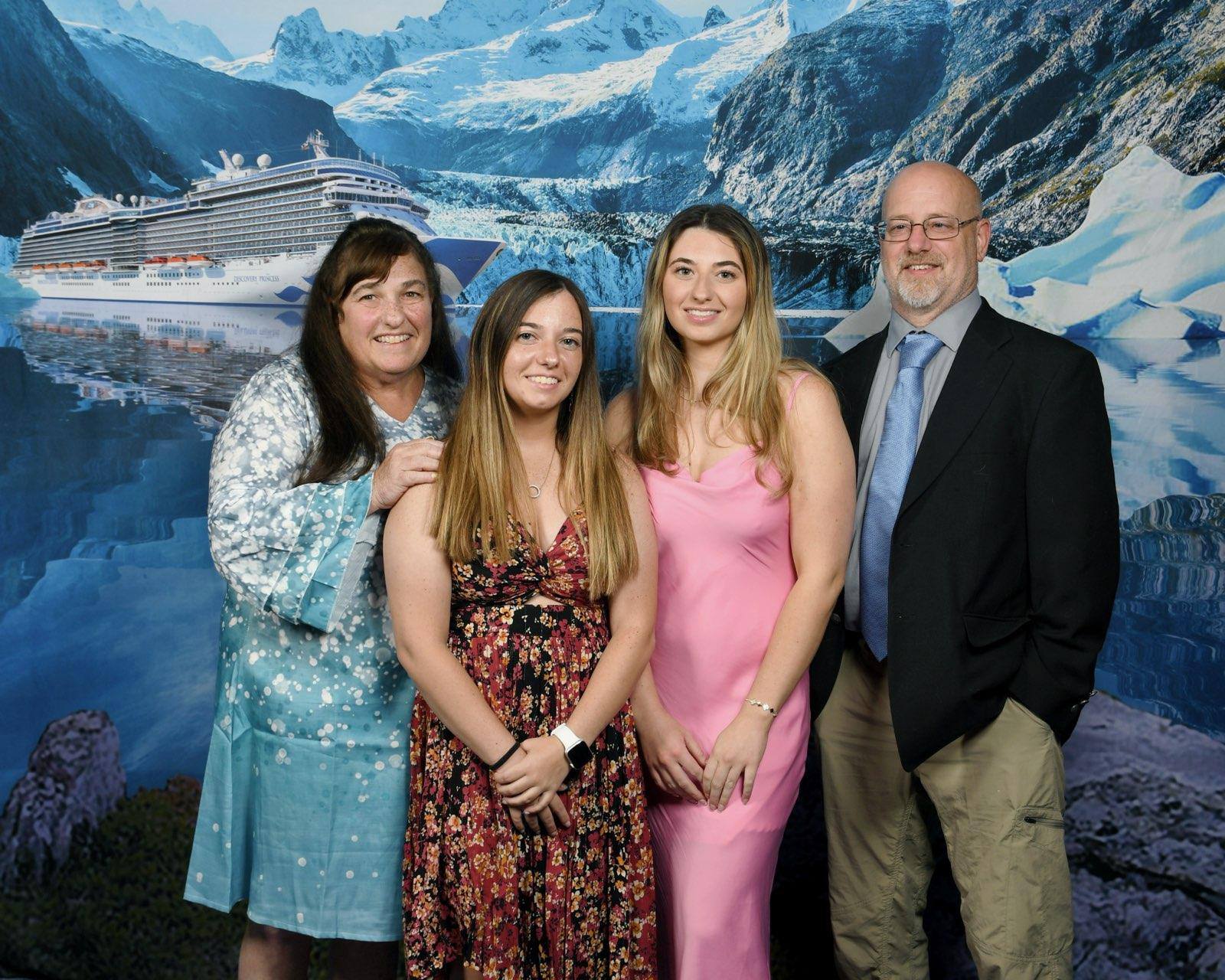 A family poses for a picture with a backdrop of a cruise ship