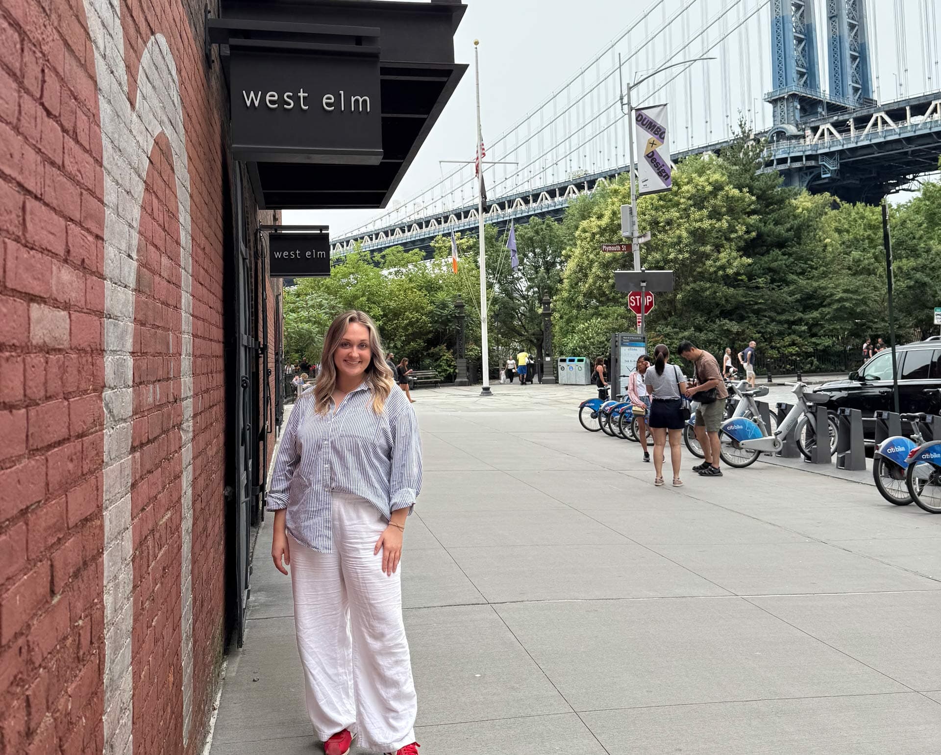 A person poses in front of a West Elm office in New York City.