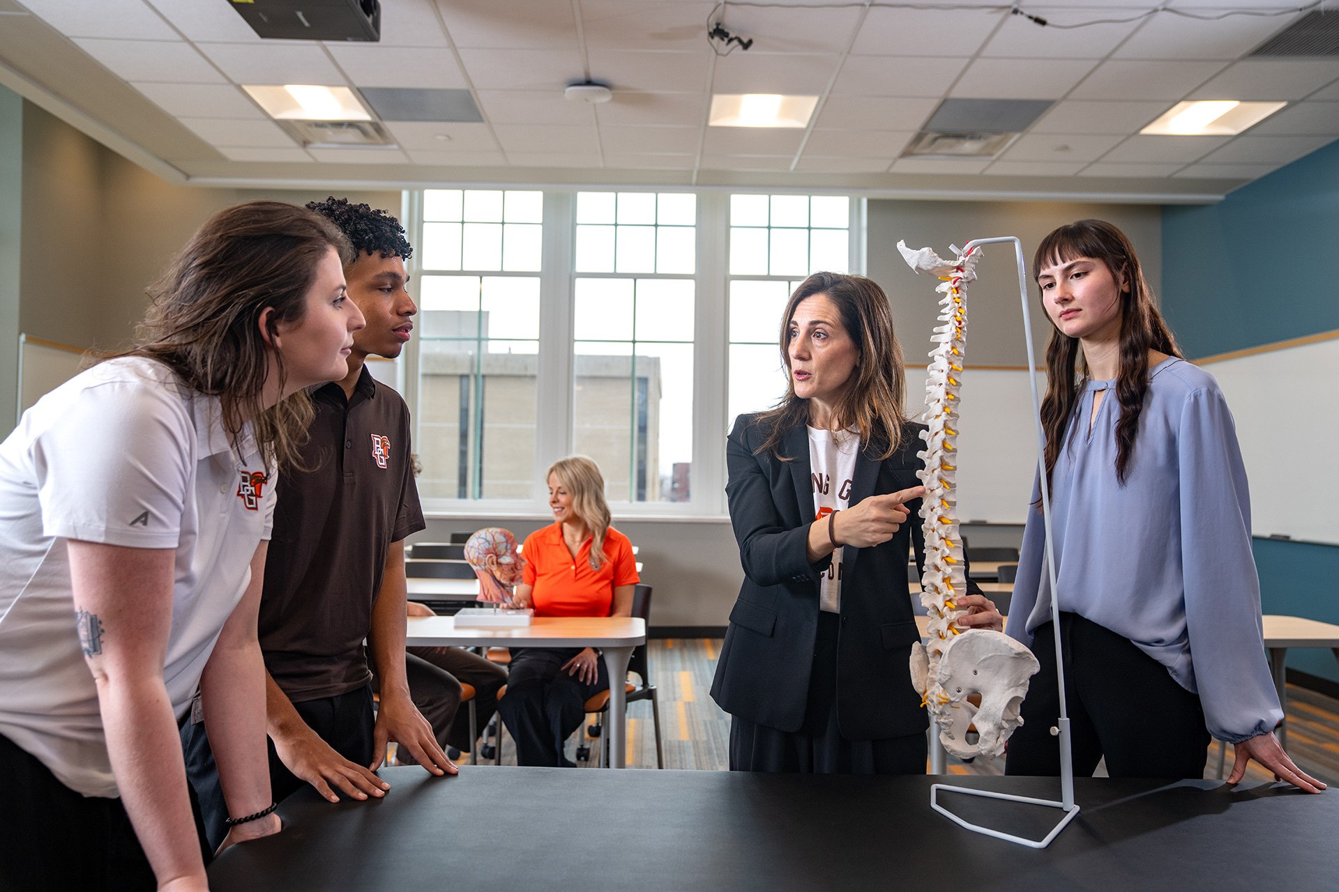An instructor teaches students using a spine model