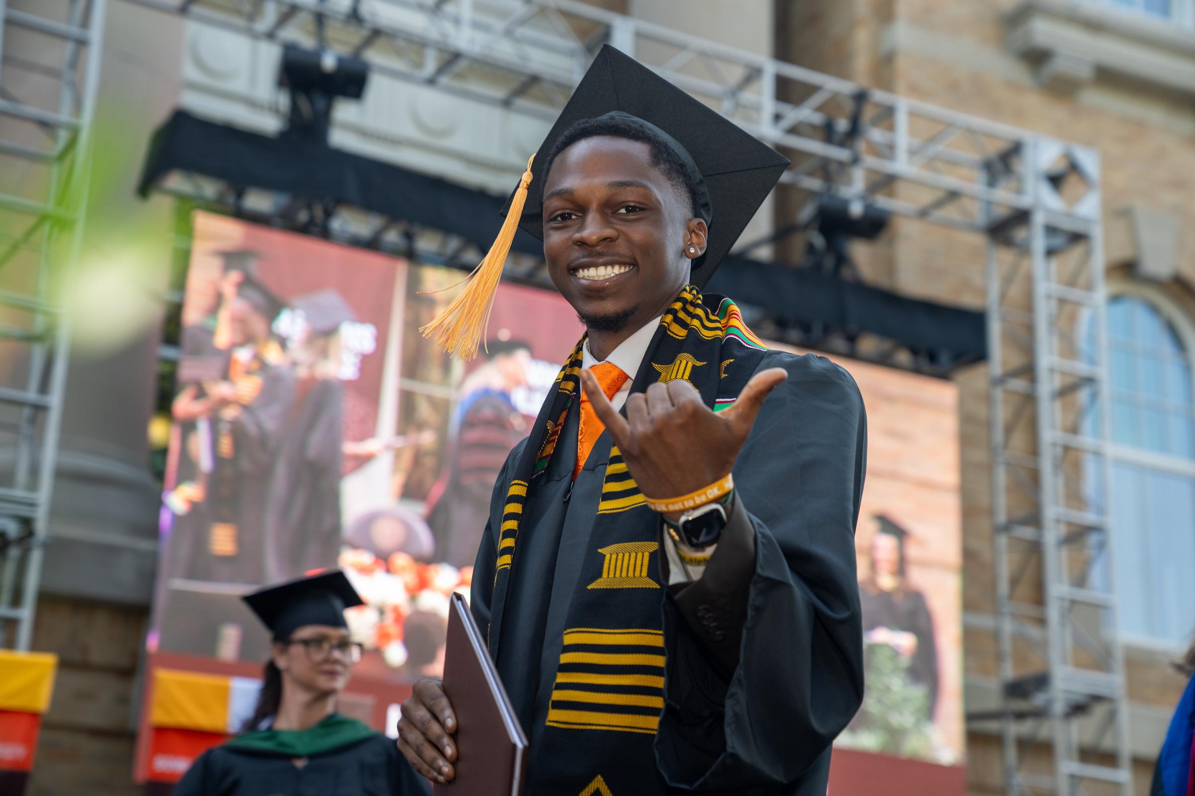 A graduate celebrates on stage after receiving diploma