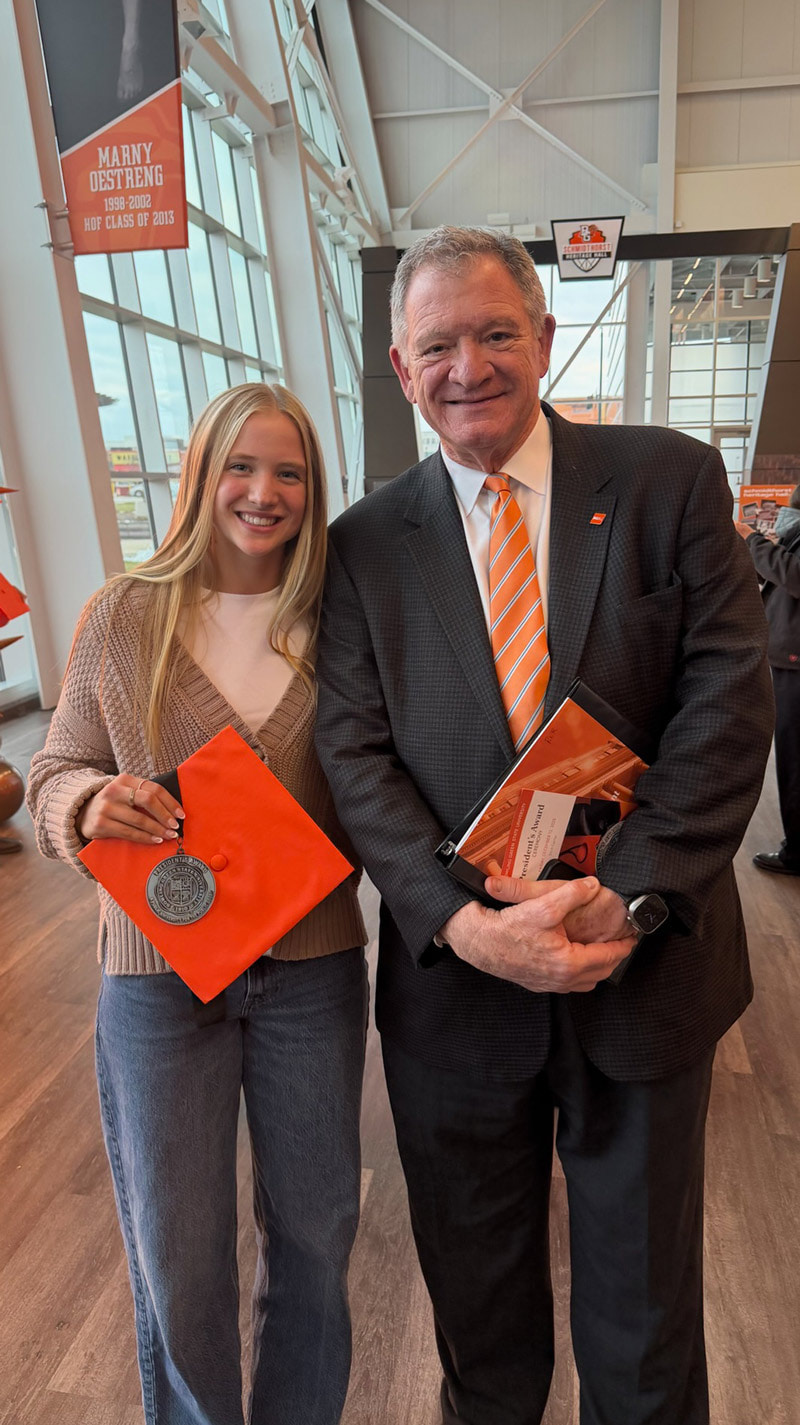 A student poses for a photo with the University president.