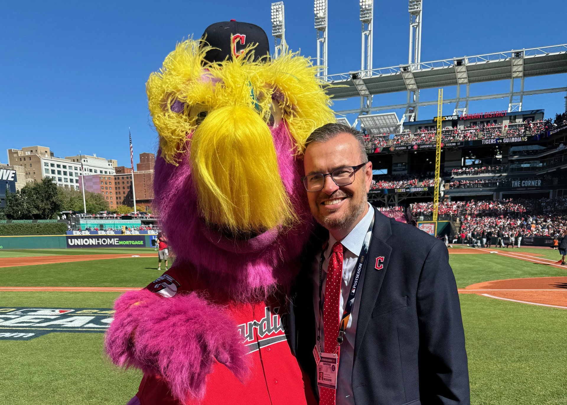 A person stands next to Cleveland Guardian's mascot, Slider.